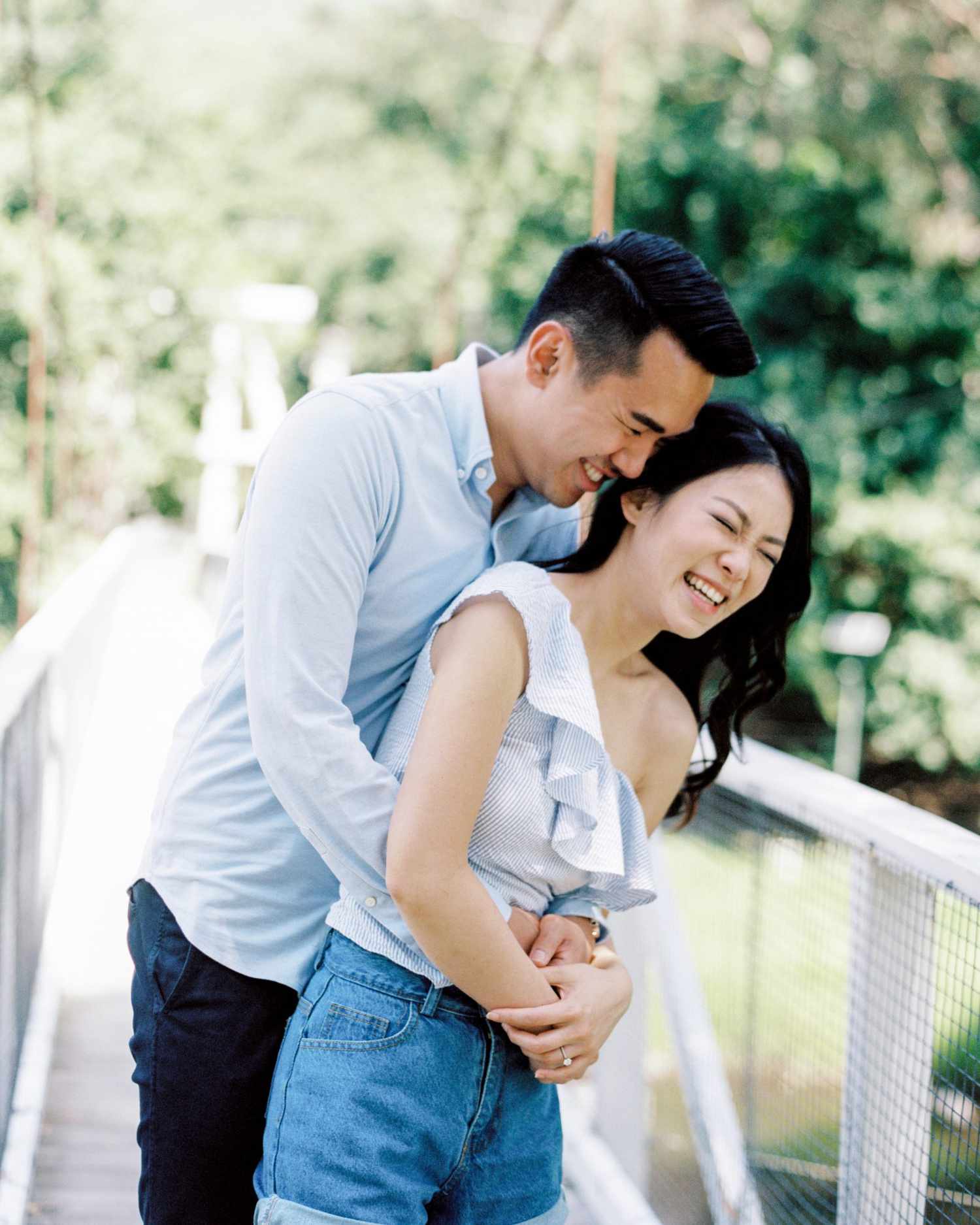 couple laughing on bridge engagement photo