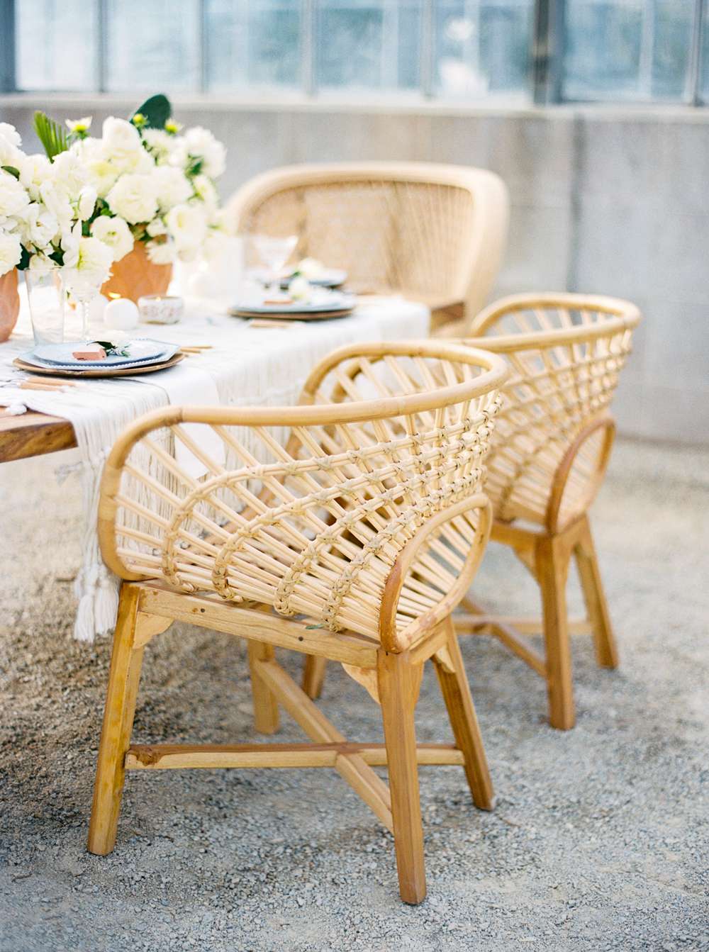 woven rattan wedding decor chairs around table decorated with white roses
