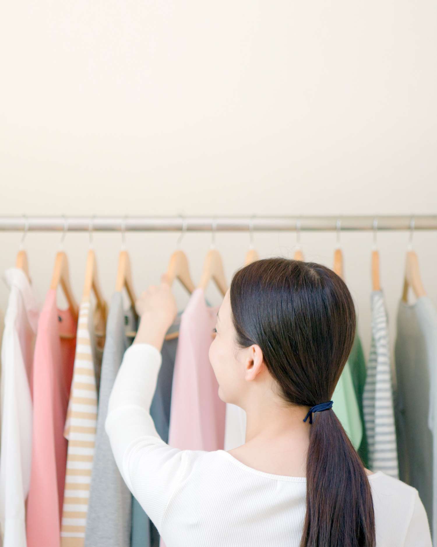 woman with ponytail looking through clothing rack