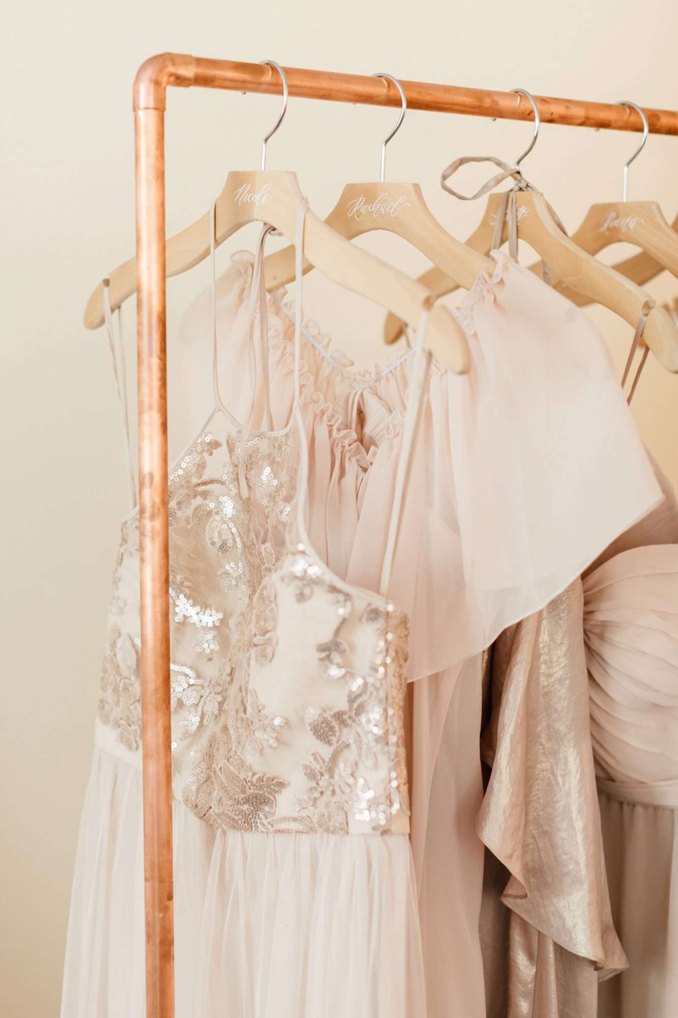 pale blush bridesmaids dresses hanging from copper clothing rack