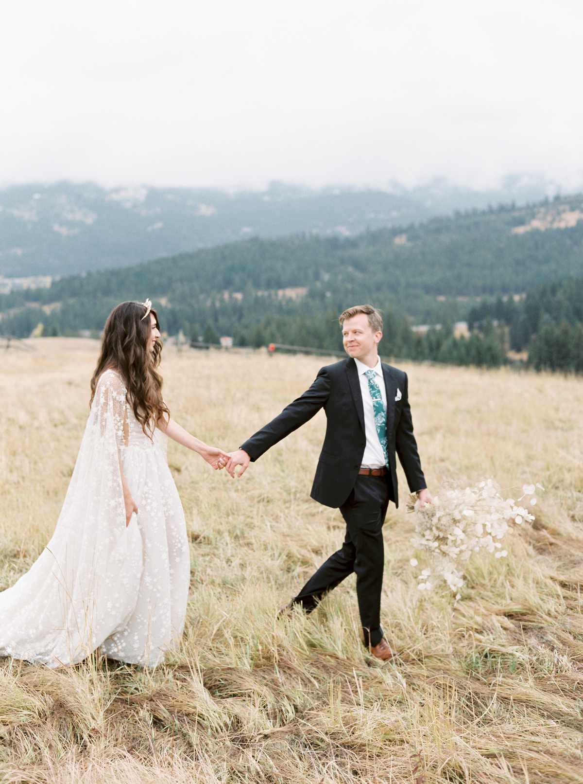 bride and groom holding hands on mountain top