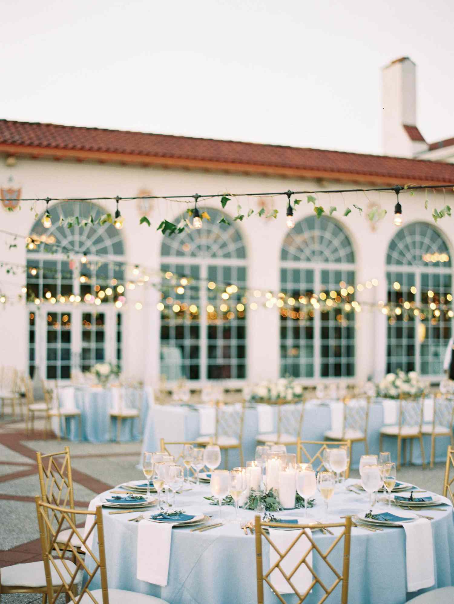 pale blue tablecloths on long and round tables with white linens, gold chairs, and tea lights