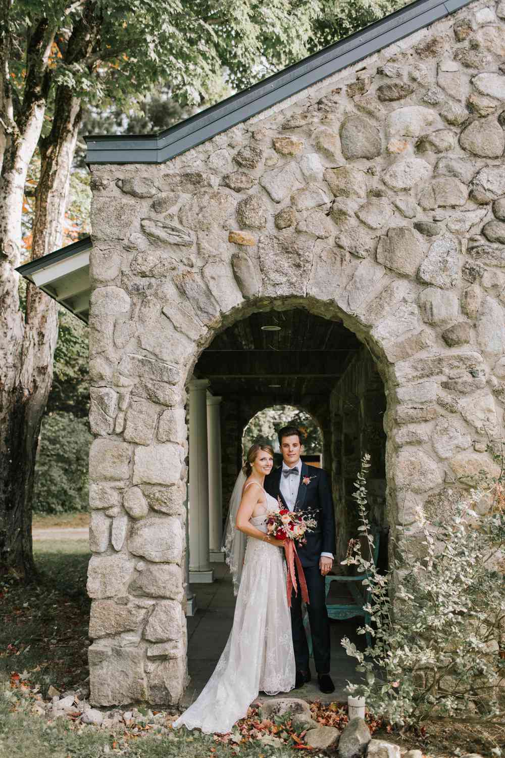 bride and groom standing under stone arch