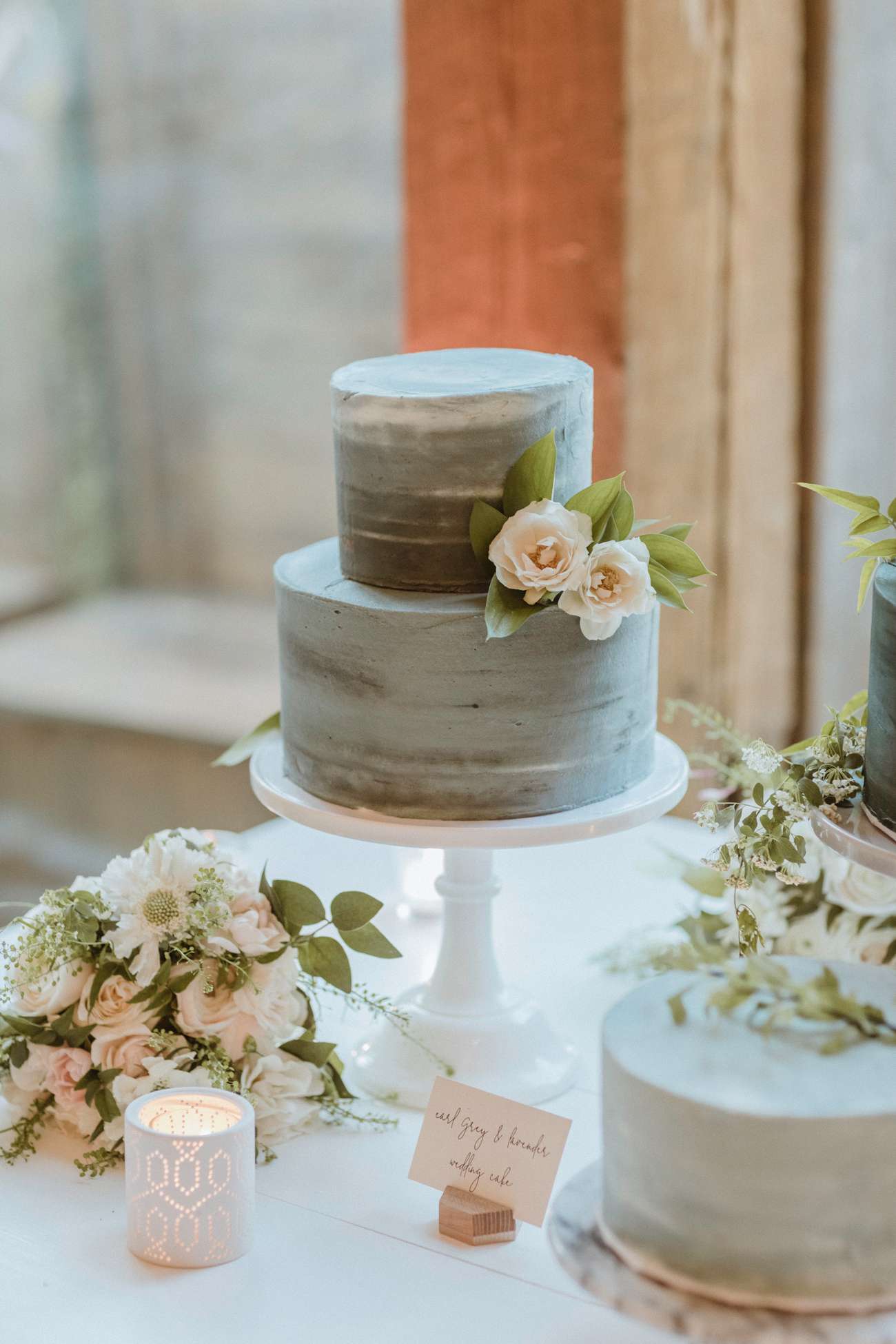 lavender and gray frosted two tiered wedding cake with floral accent