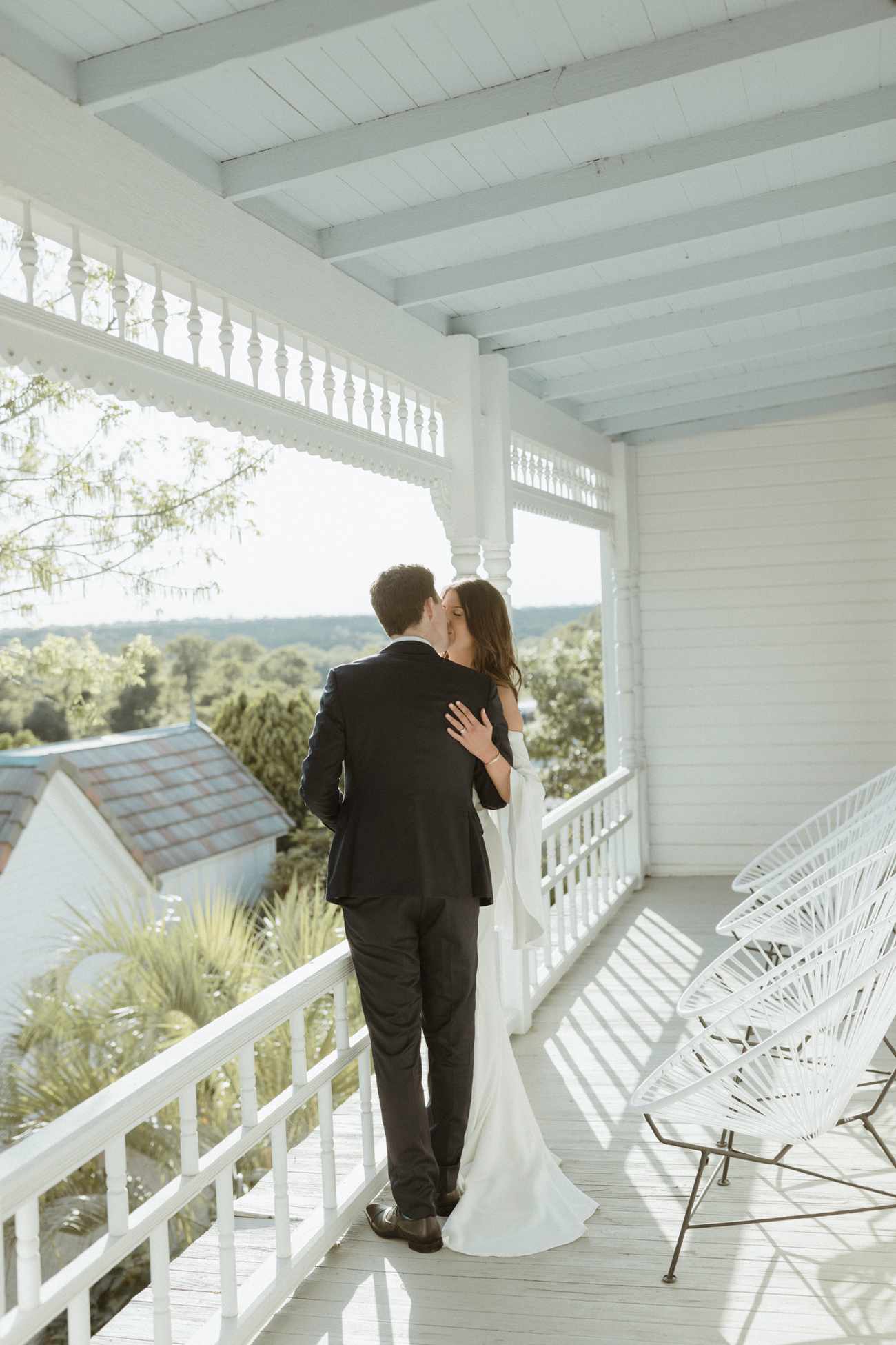 bride and groom kissing on white balcony