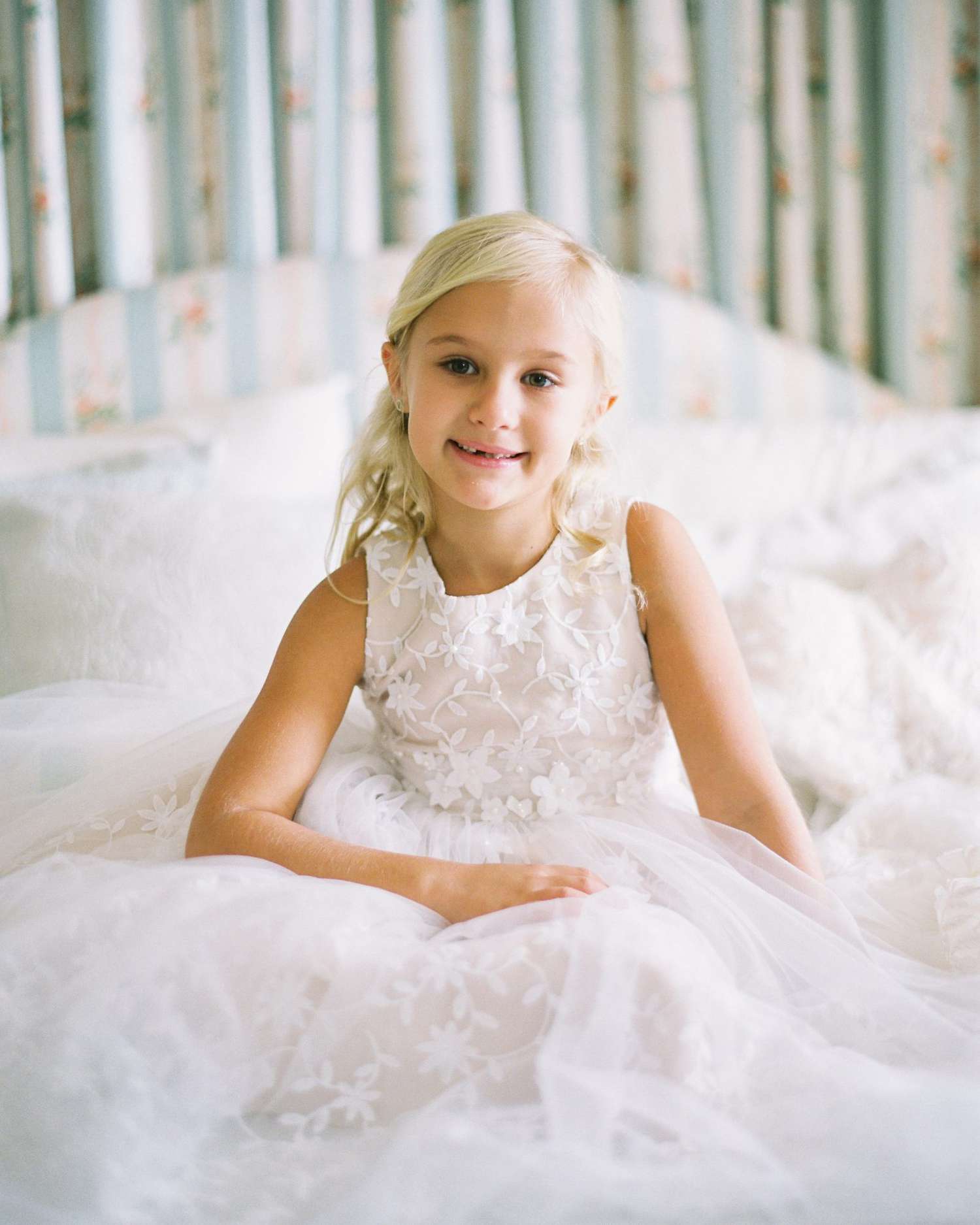 flower girl sitting in matching bridal dress