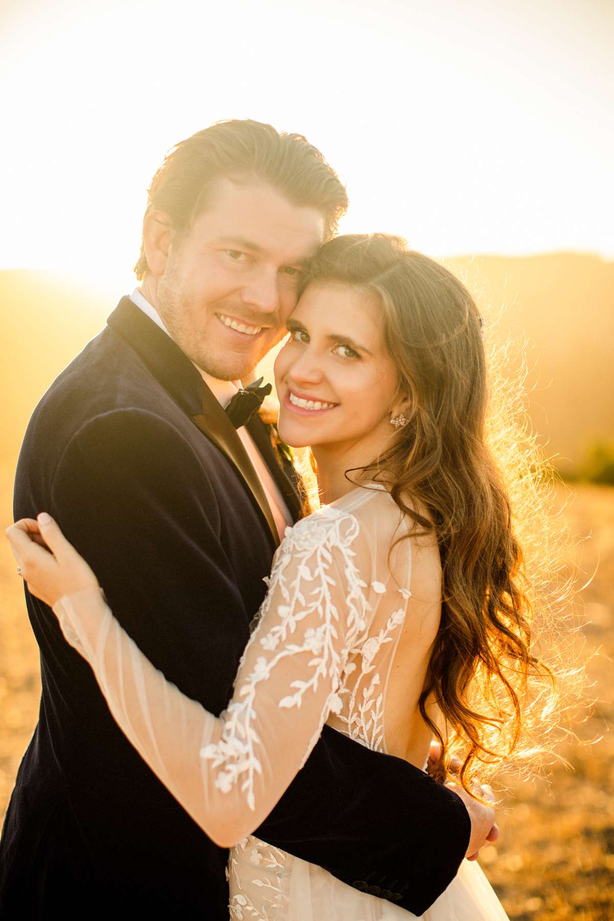 bride and groom hold each other smiling on california hillside