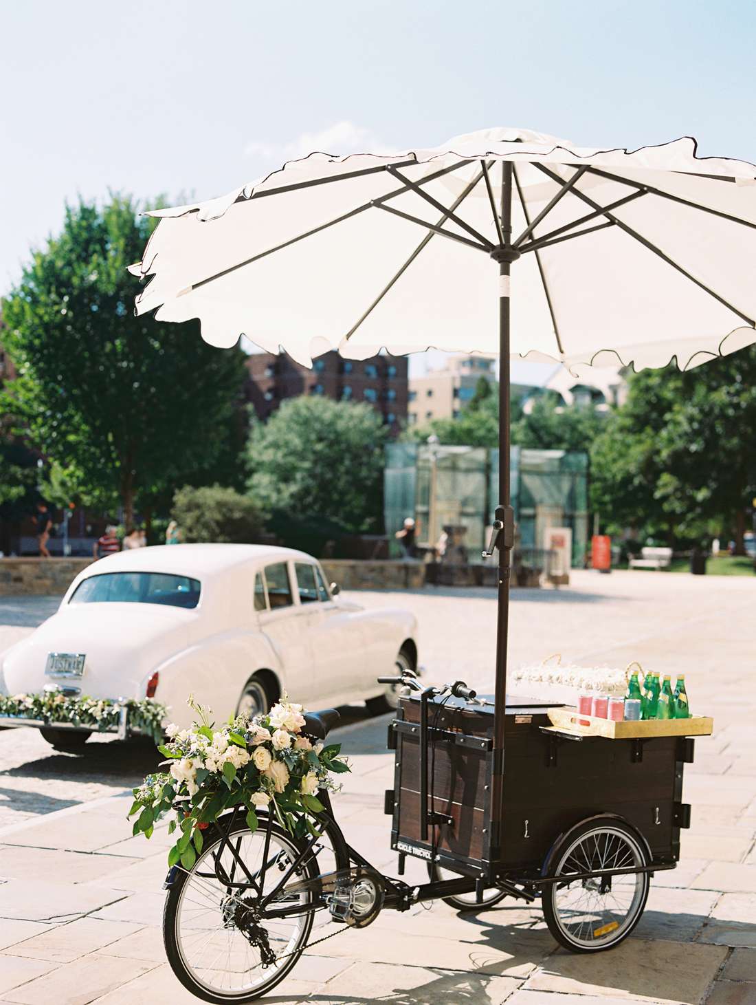 rose bicycle cart with white umbrella next to white vintage car