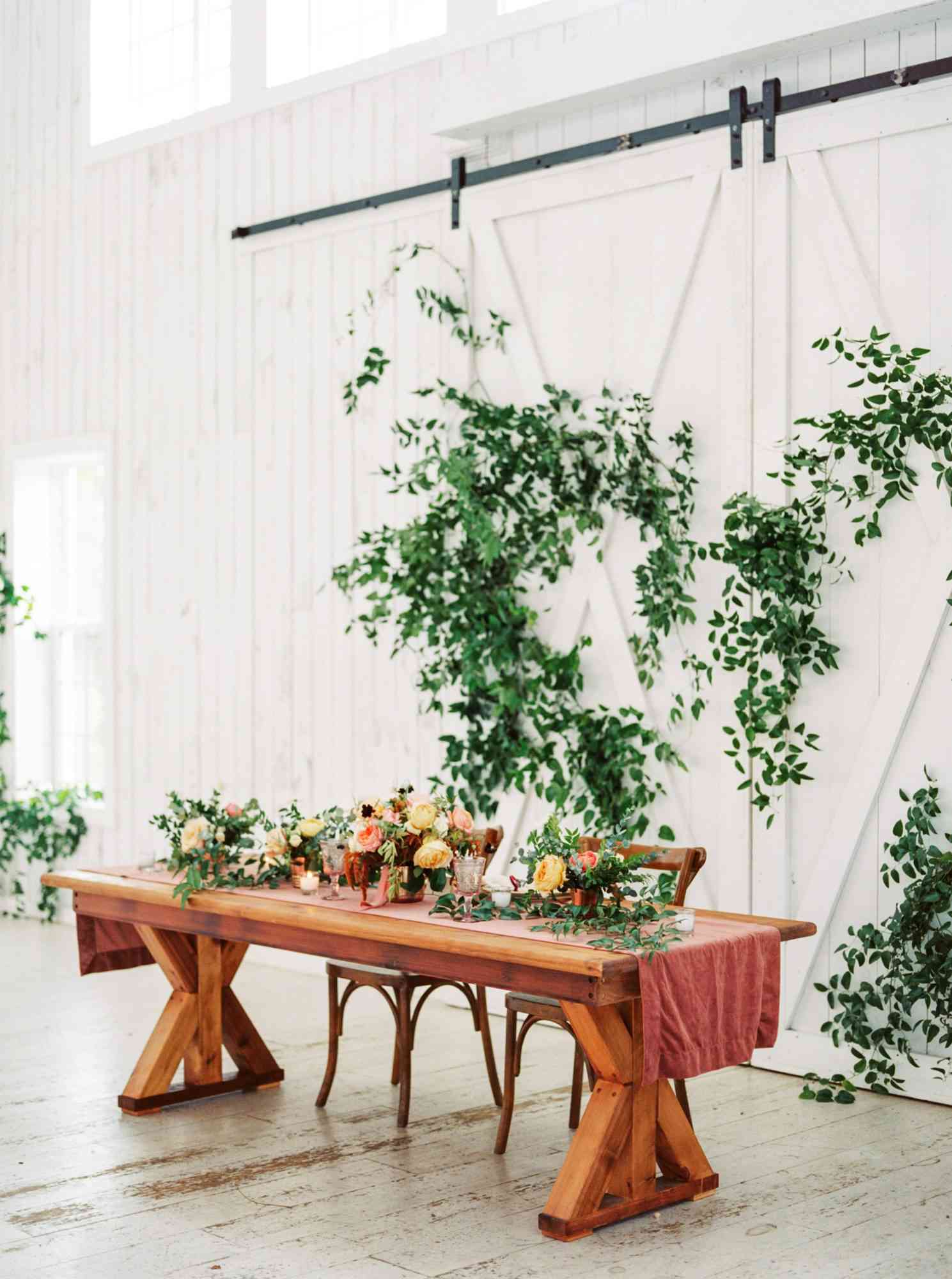 sweetheart table wooden with green leaf accented back drop
