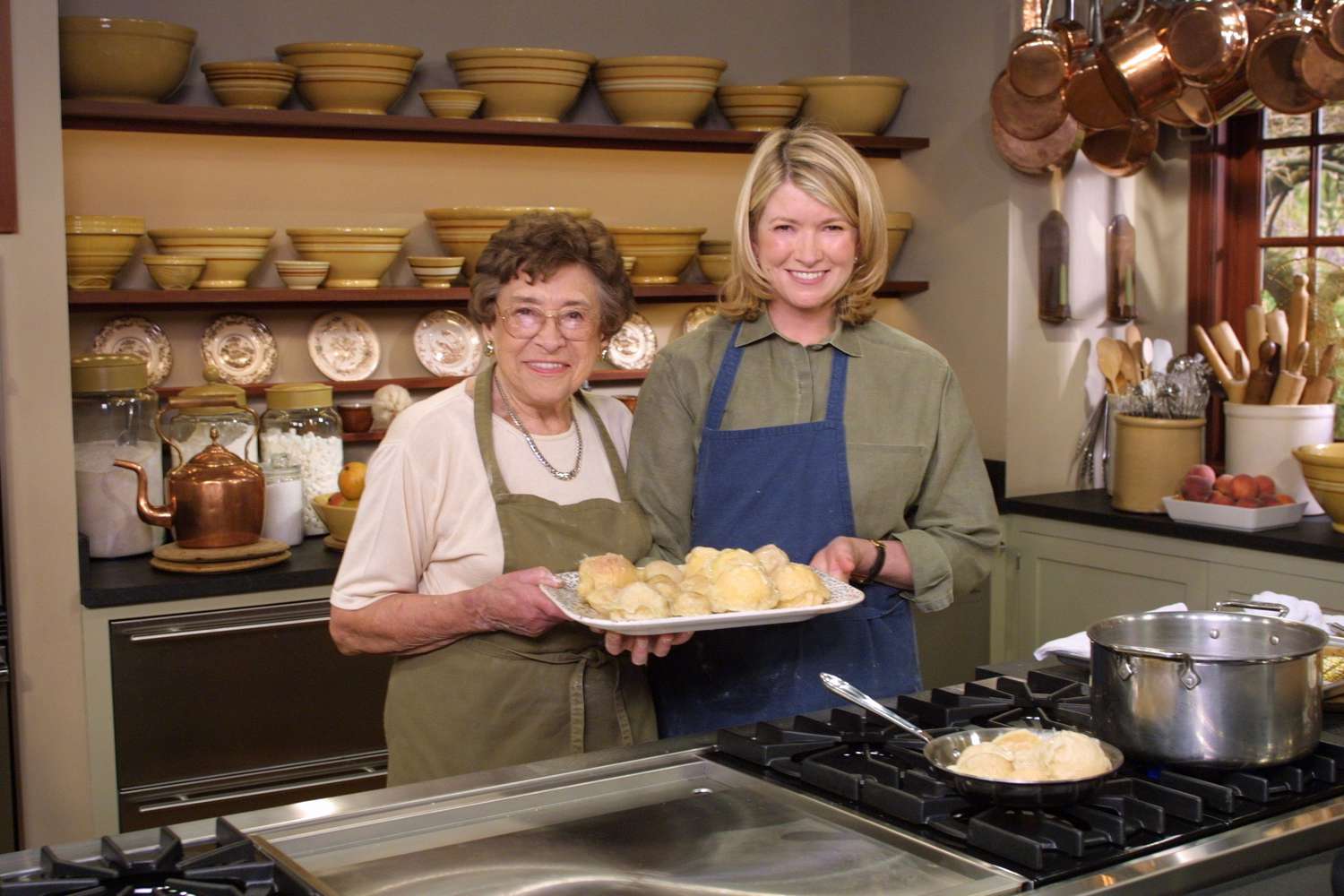 martha stewart and another woman holding baked goods in kitchen