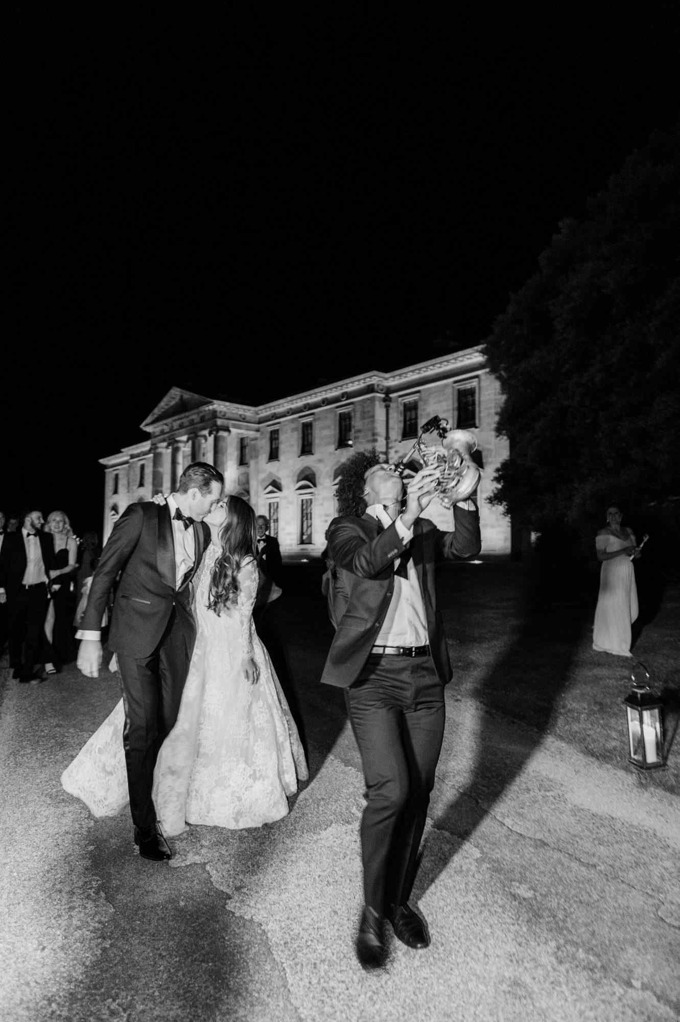 bride and groom kissing while saxophonist plays