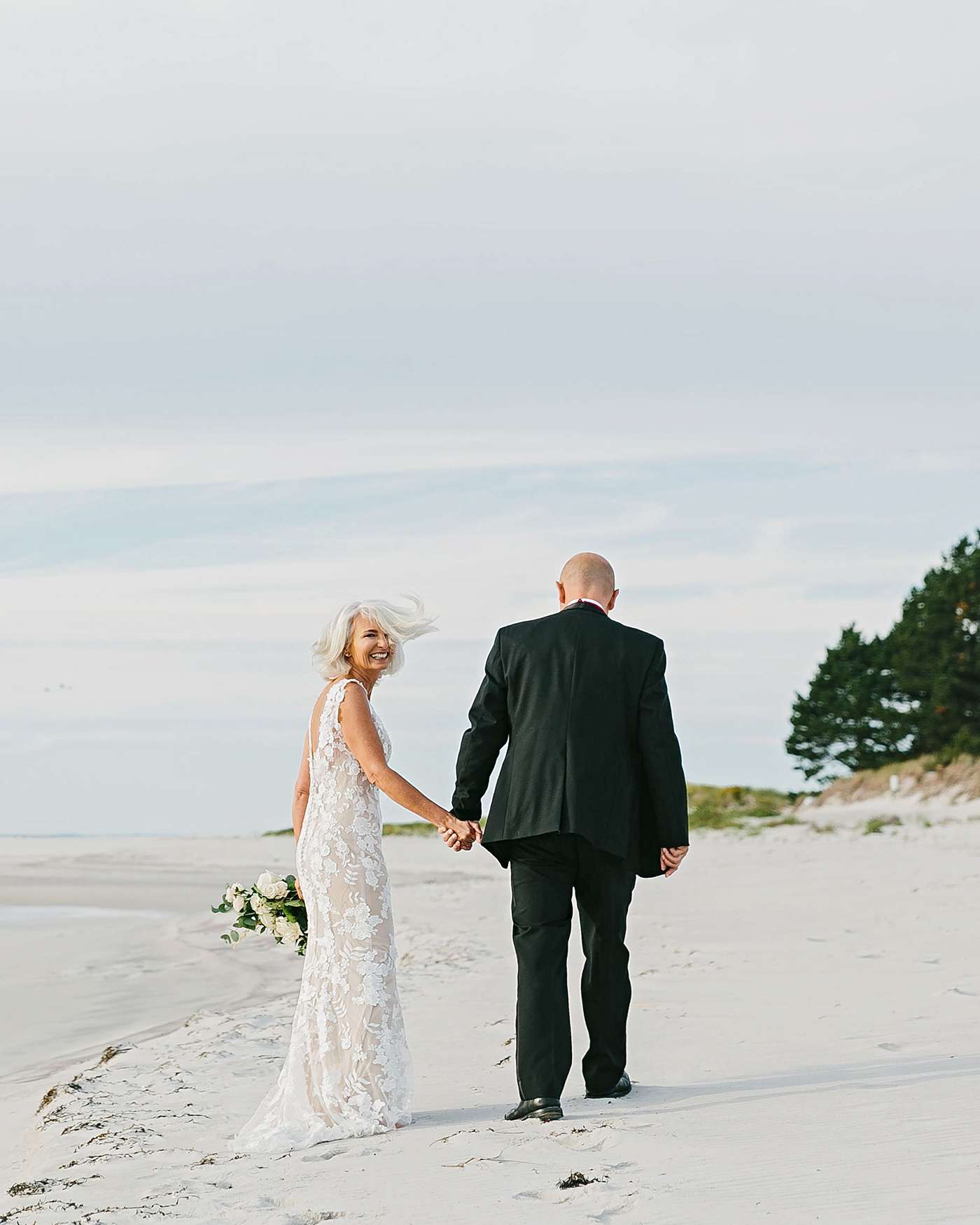 bride and groom walking away on beach