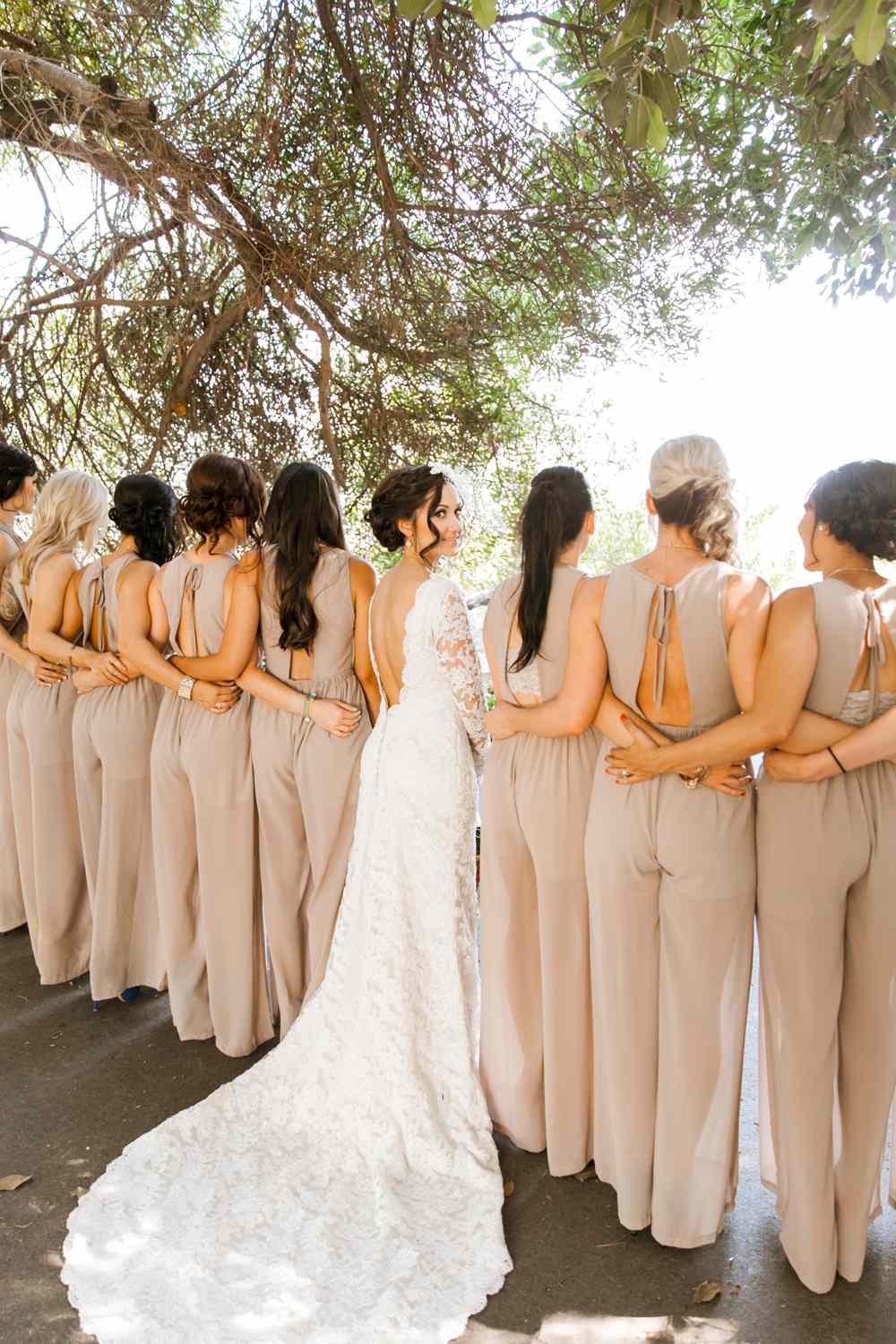 the backs of women wearing bridesmaids jumpsuits