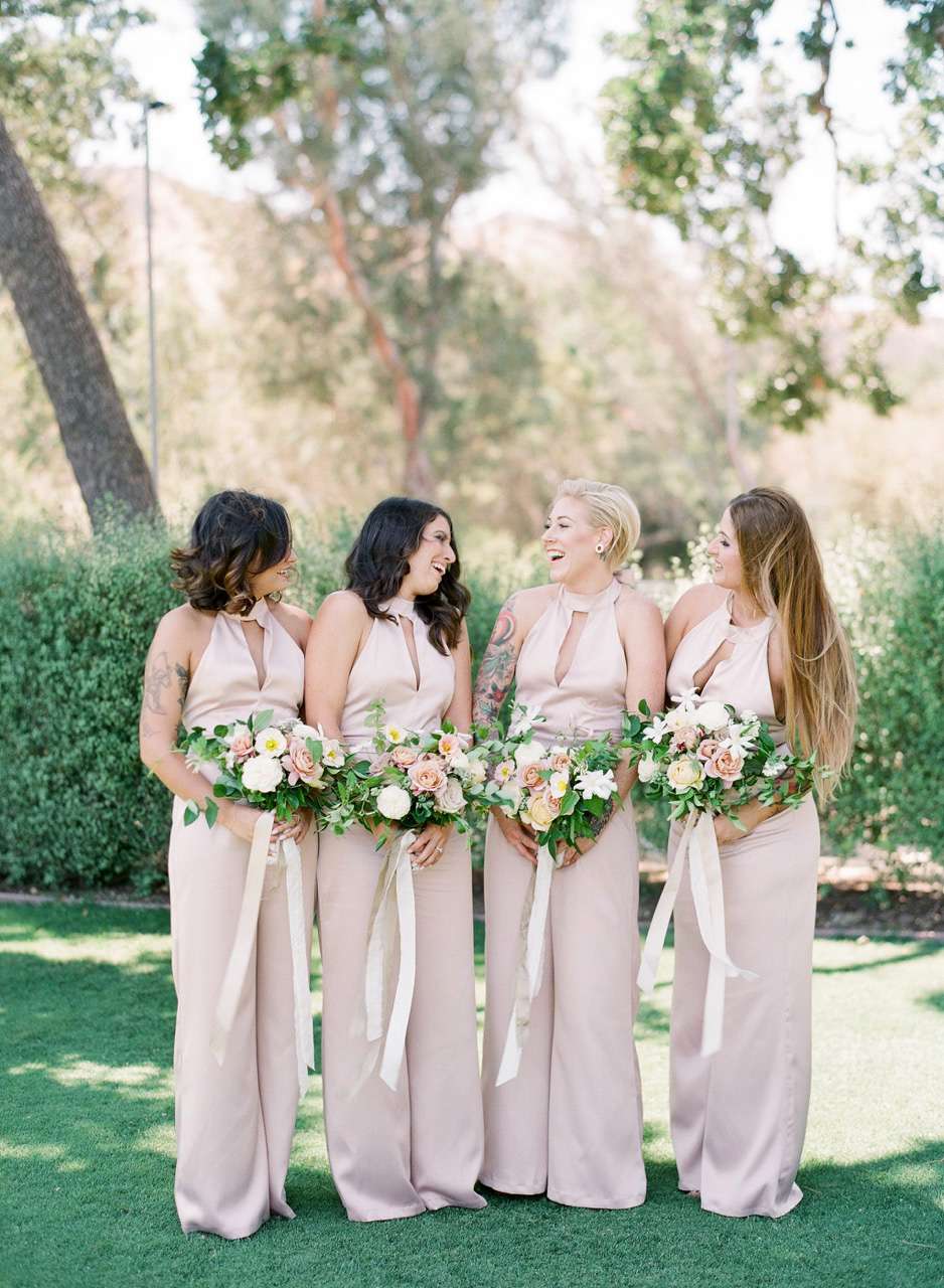 women standing on lawn wearing high neckline with cutout bridesmaids jumpsuits