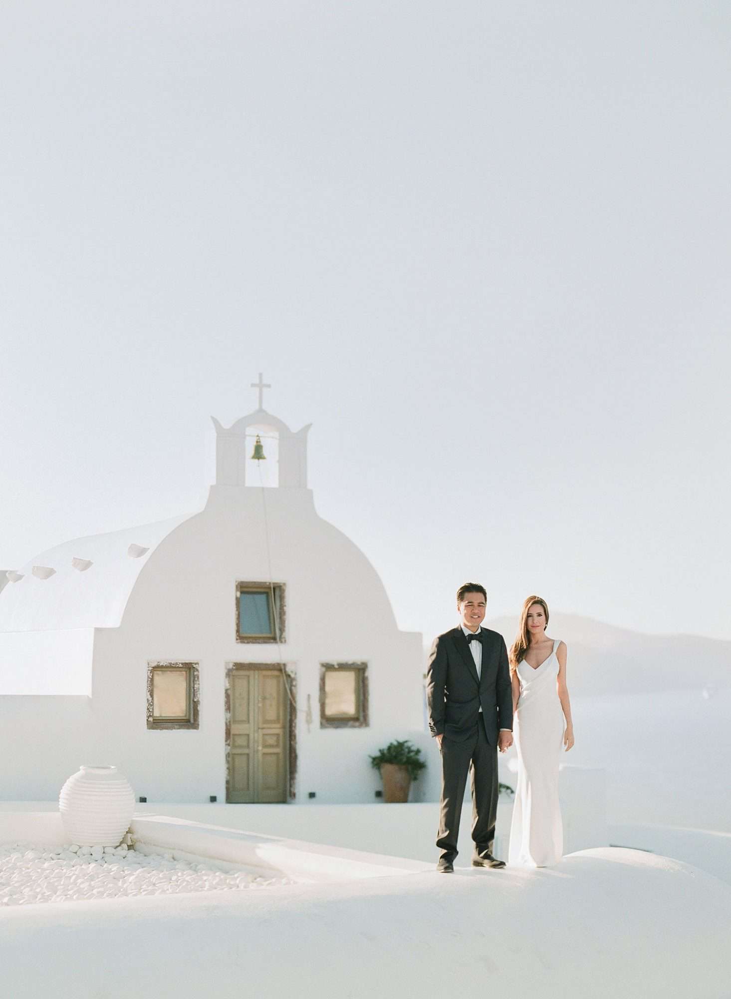 bride and groom outside of white Grecian church