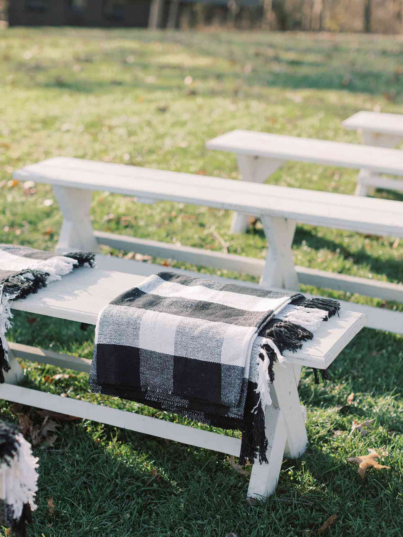 black and white buffalo check blanket wraps on white wedding ceremony benches