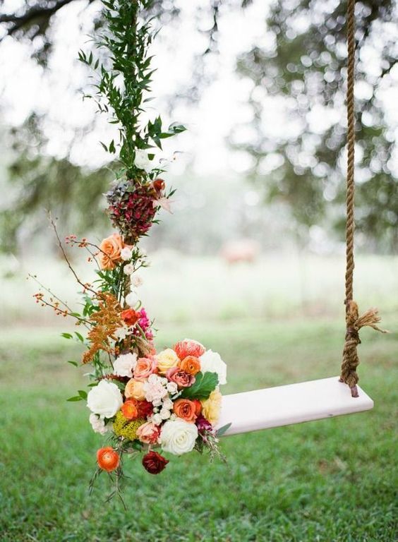 swing decorated with berries, orange, red, and yellow roses along with rusty greenery