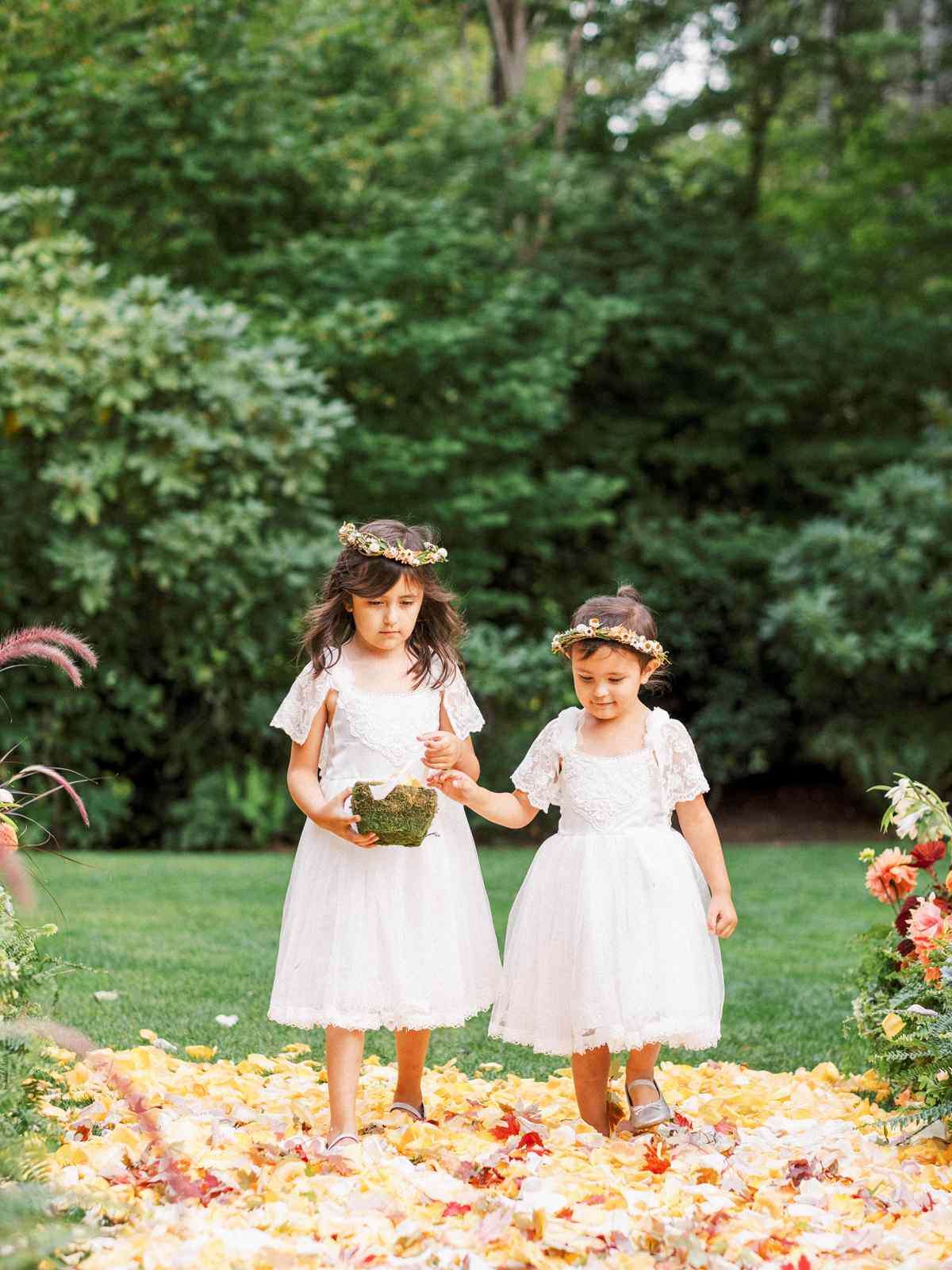 two flower girls wearing white tea length dresses and flower crowns