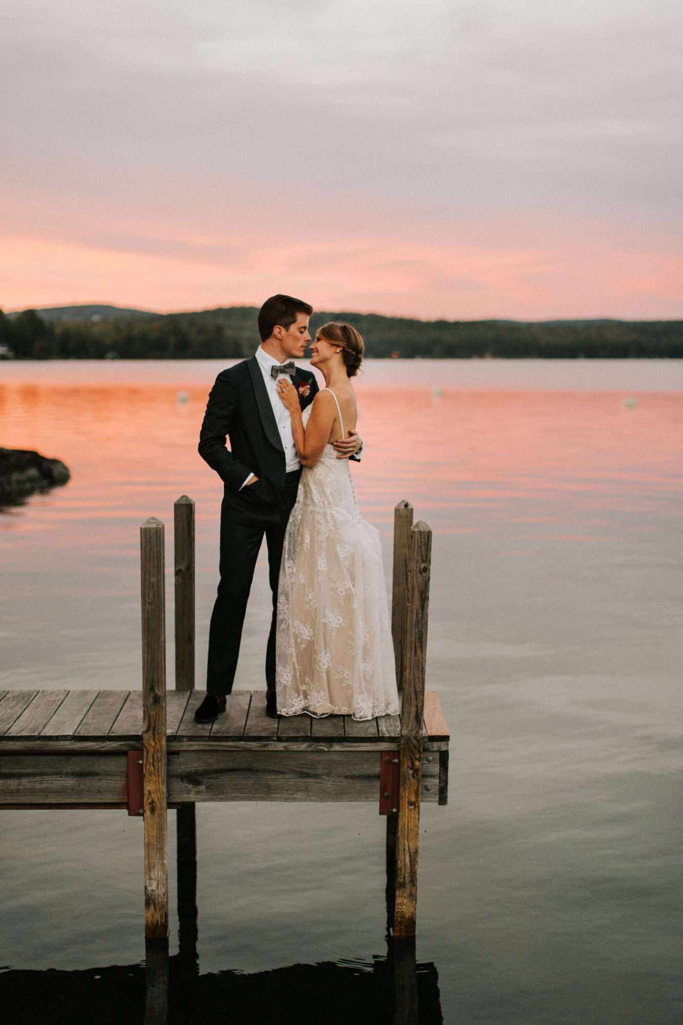 bride and groom standing on the pier at sunset