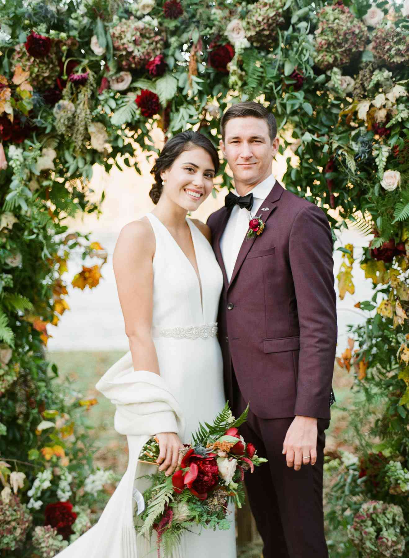 bride and groom standing under floral arch