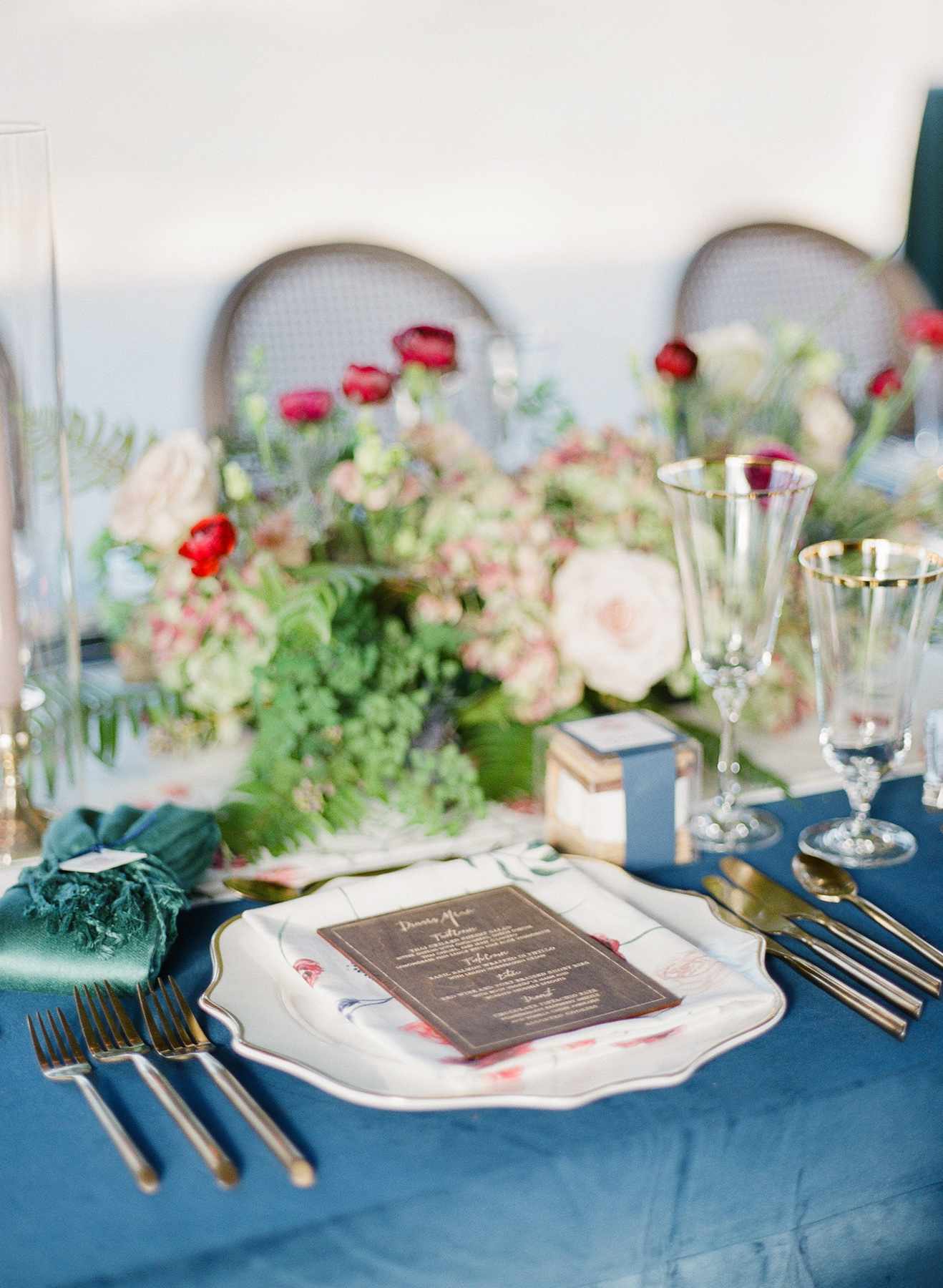 gold rimmed place settings and gold flatware on blue table linens
