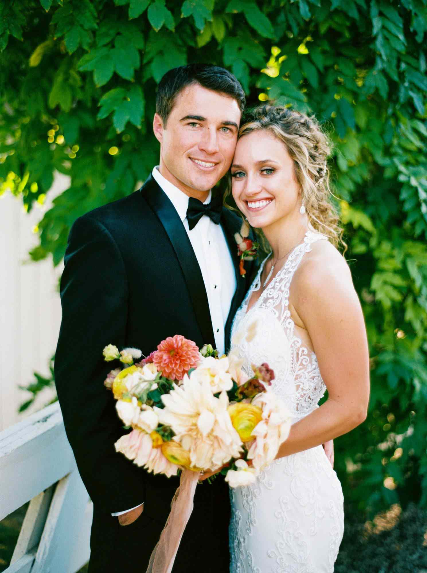bride and groom pose in wedding attire outdoors