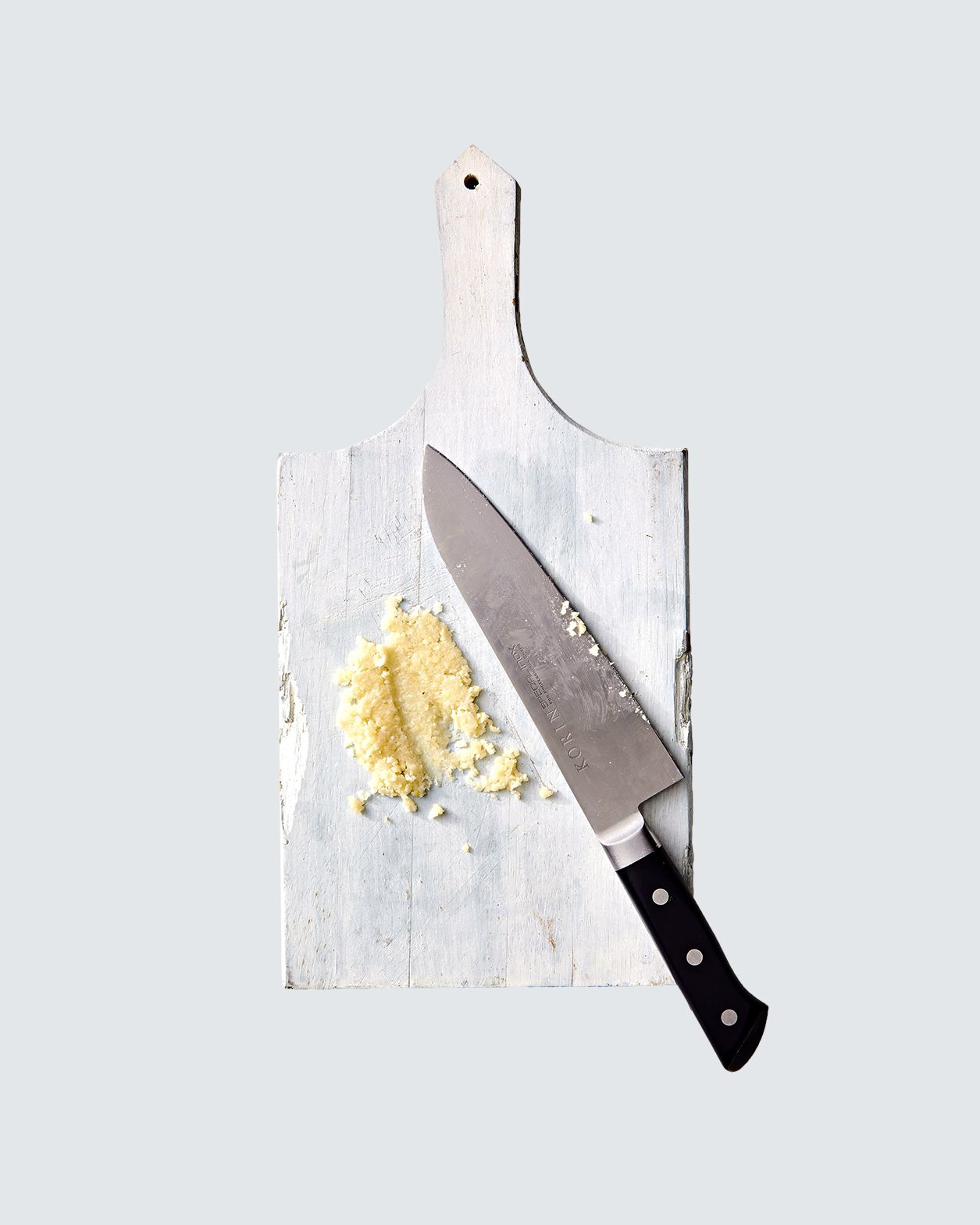 garlic mashed for dressing on cutting board with knife