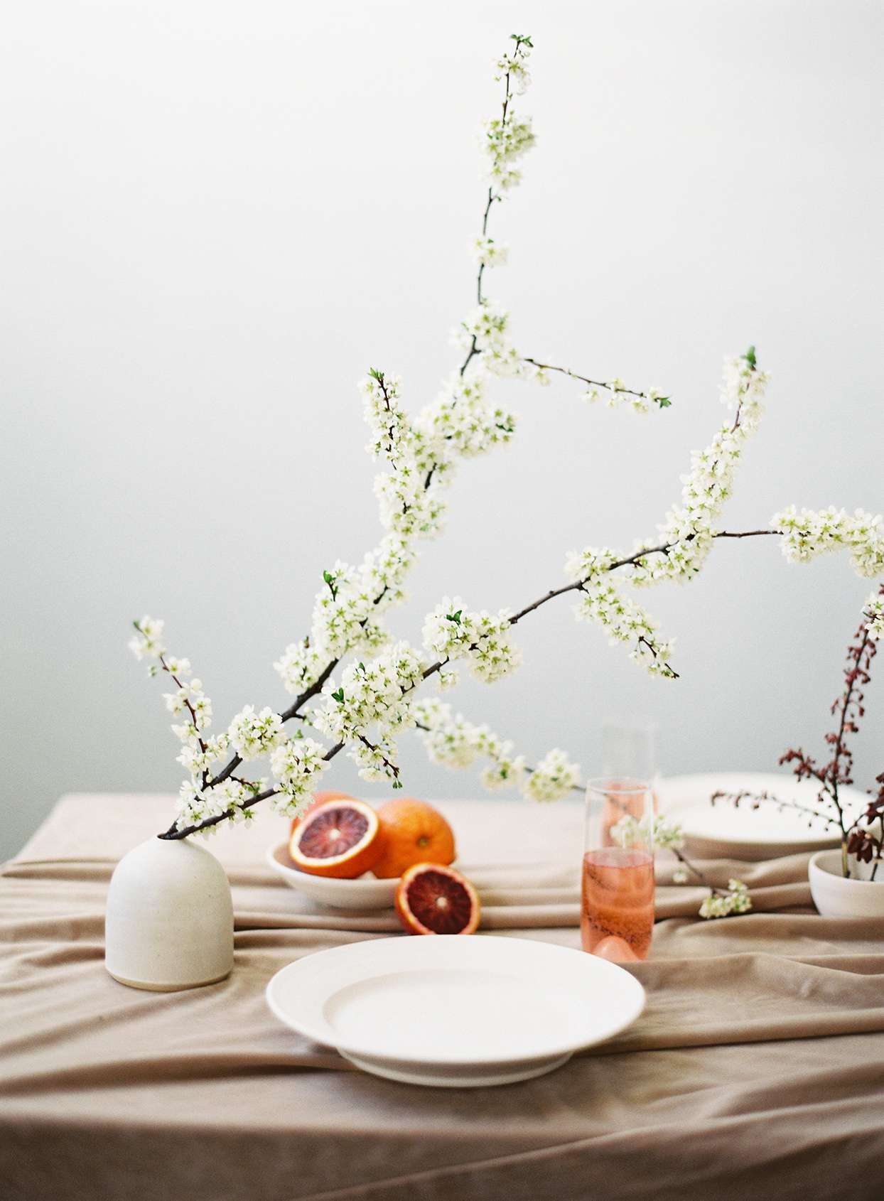 minimalist ikebana short vase with tall flowers on table with oranges