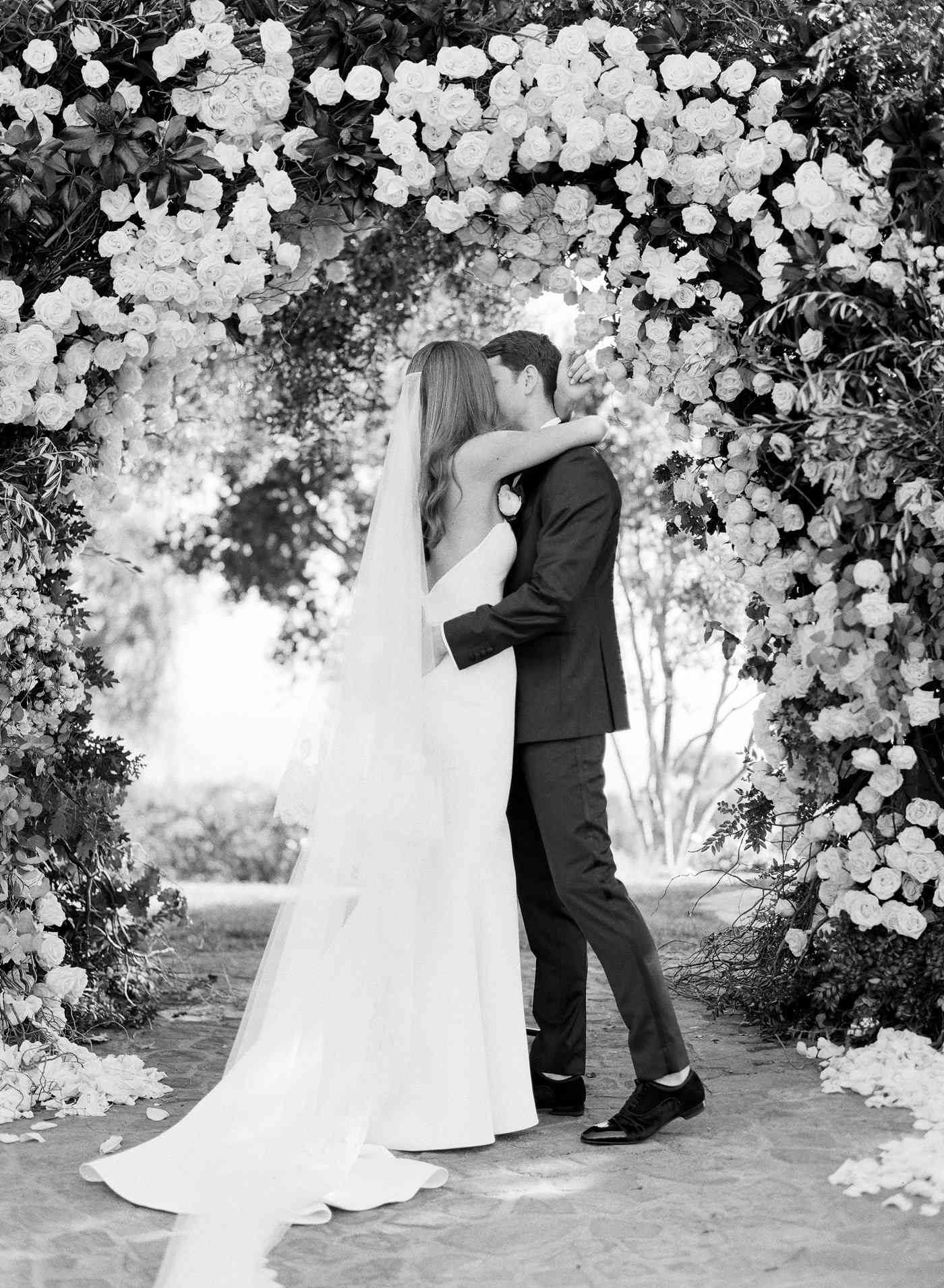 Gloria and Jordan kissing under arch black and white