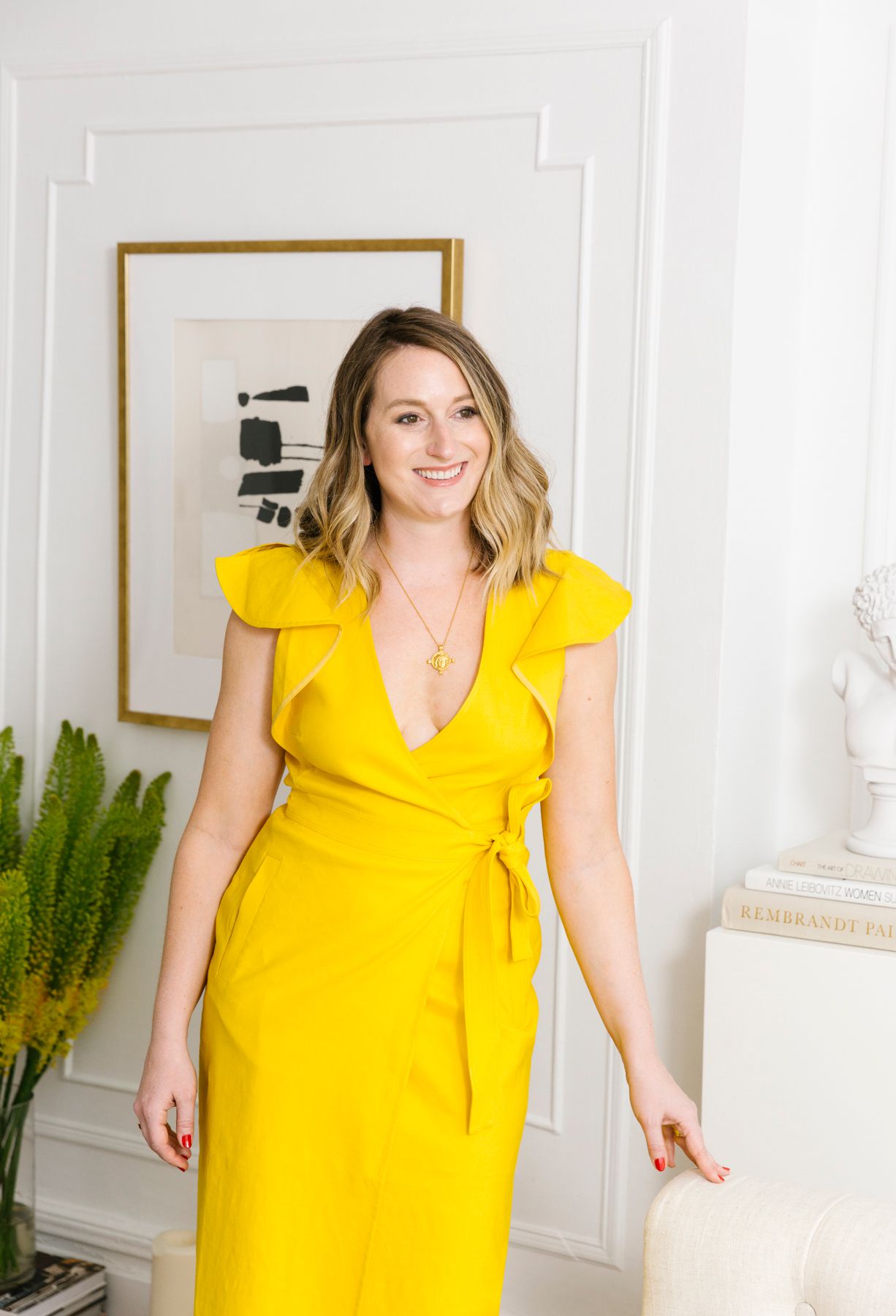 shelby in bright yellow dress standing in nyc apartment