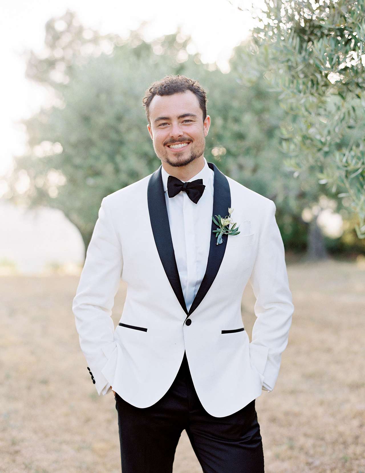 groom posing in white jacket tuxedo