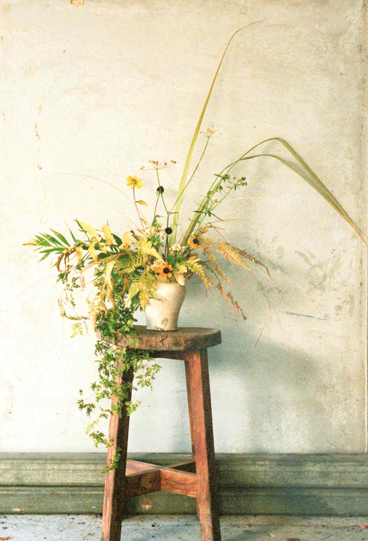 vase of wildflowers atop wooden stool