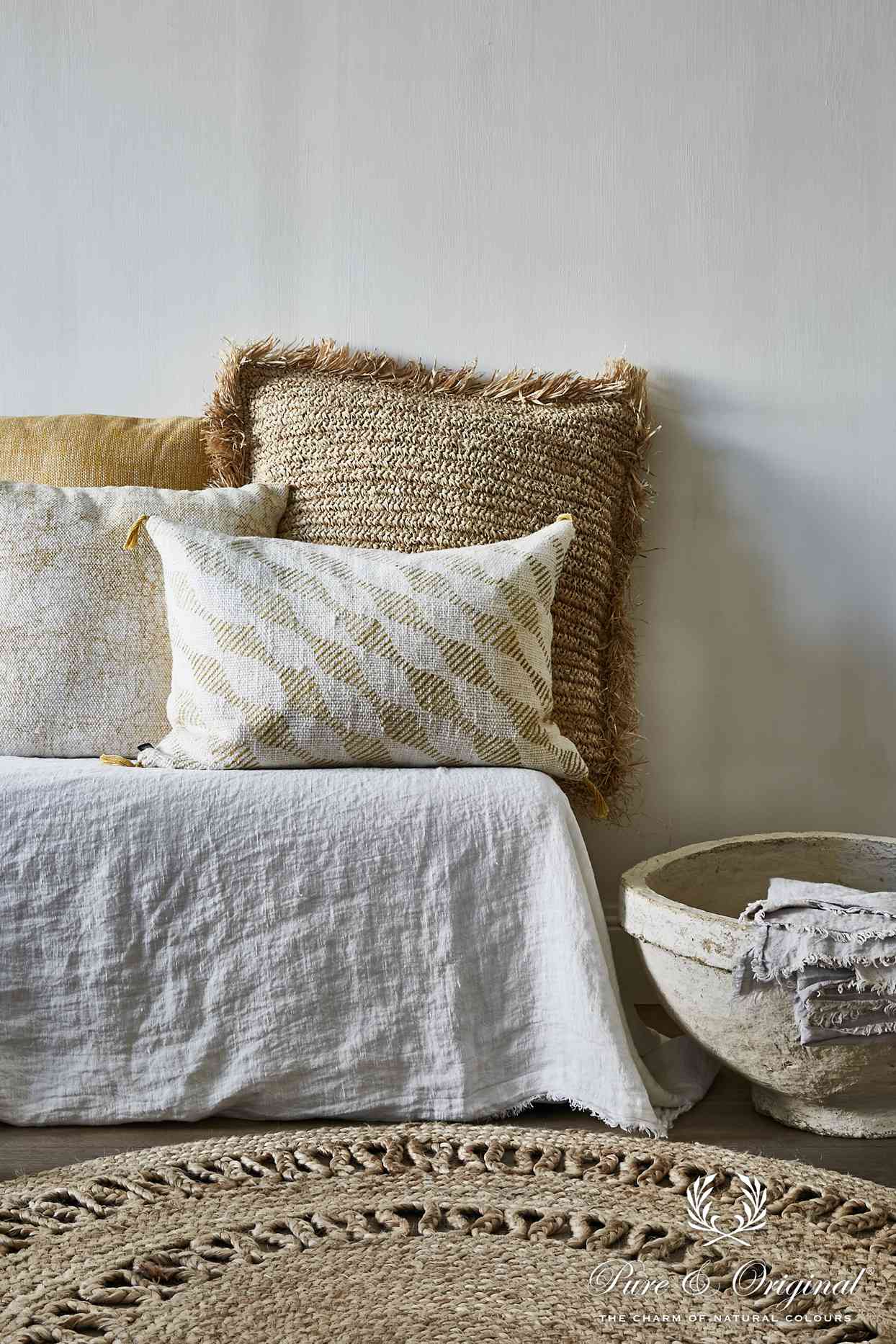 沙发床，中性色抱枕和编织地毯