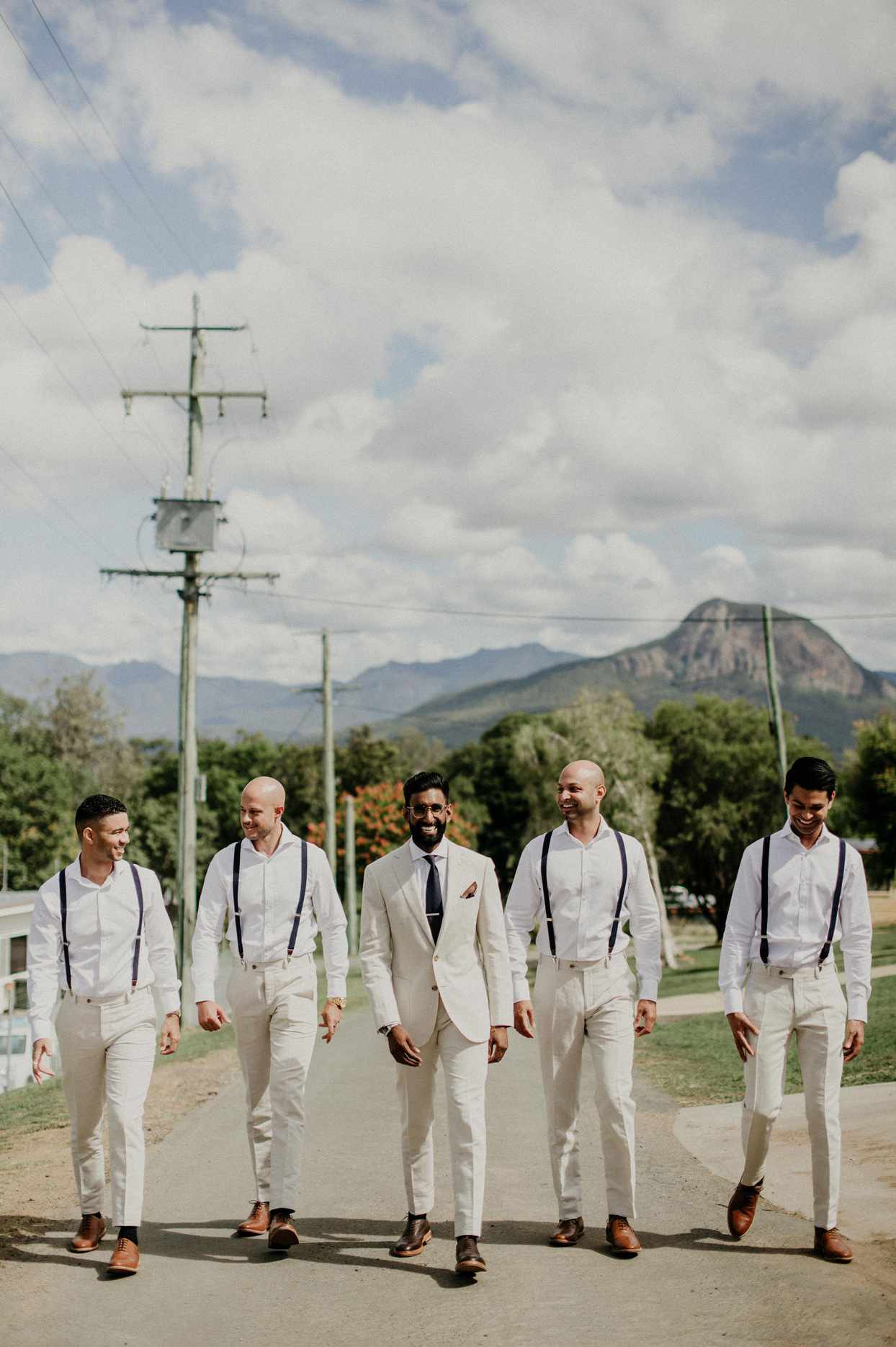 groom walking with groomsmen in white outfits
