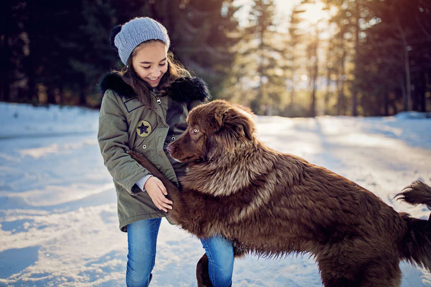 Little girl is playing with her dog in the snowy forest