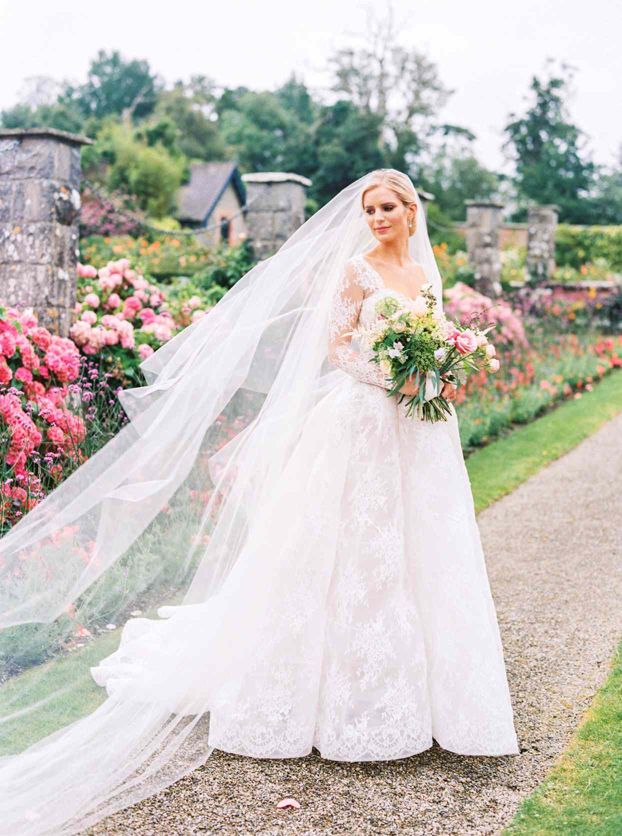 bride wearing a lace long sleeve sweetheart neckline Monique Lhuillier lace ball gown with long veil