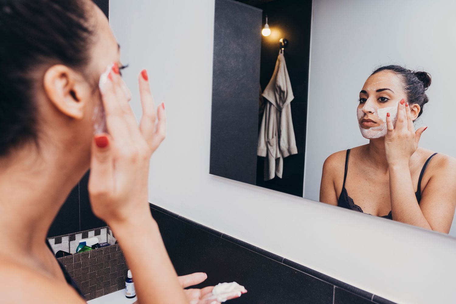 woman in front of mirror applying face mask