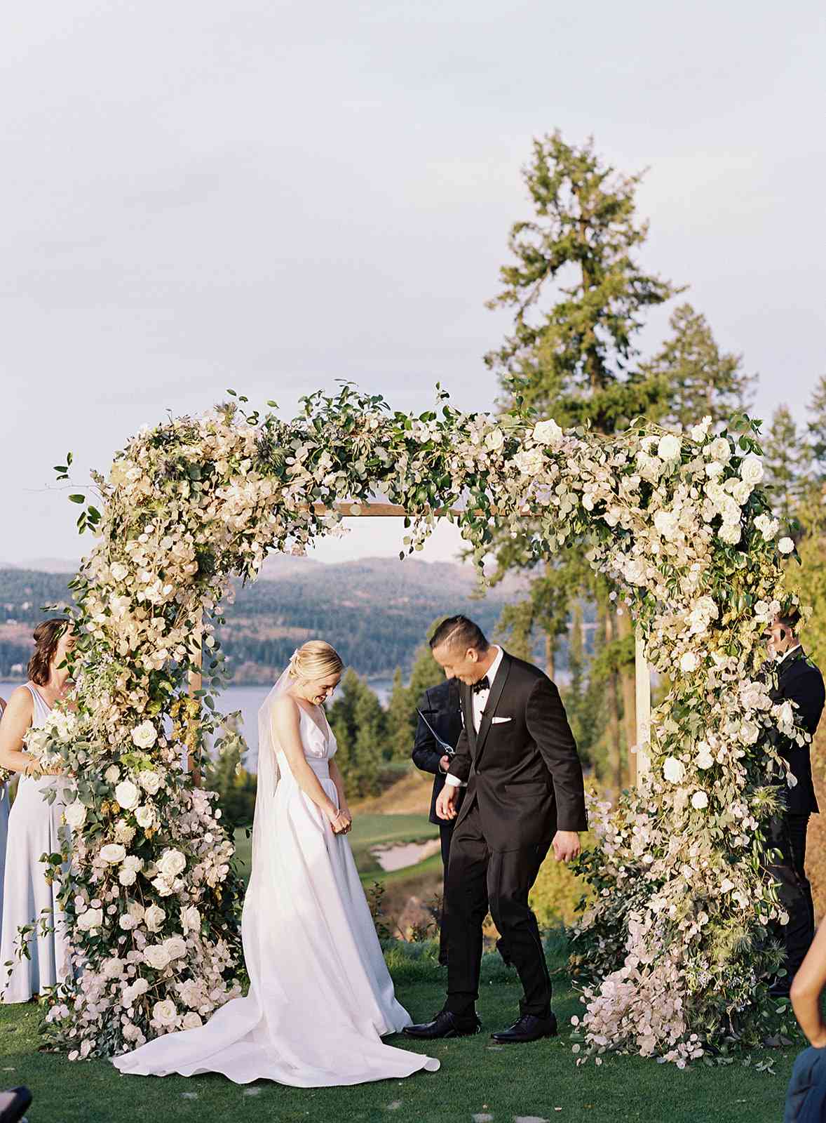 bride and groom next to floral wedding arch outside