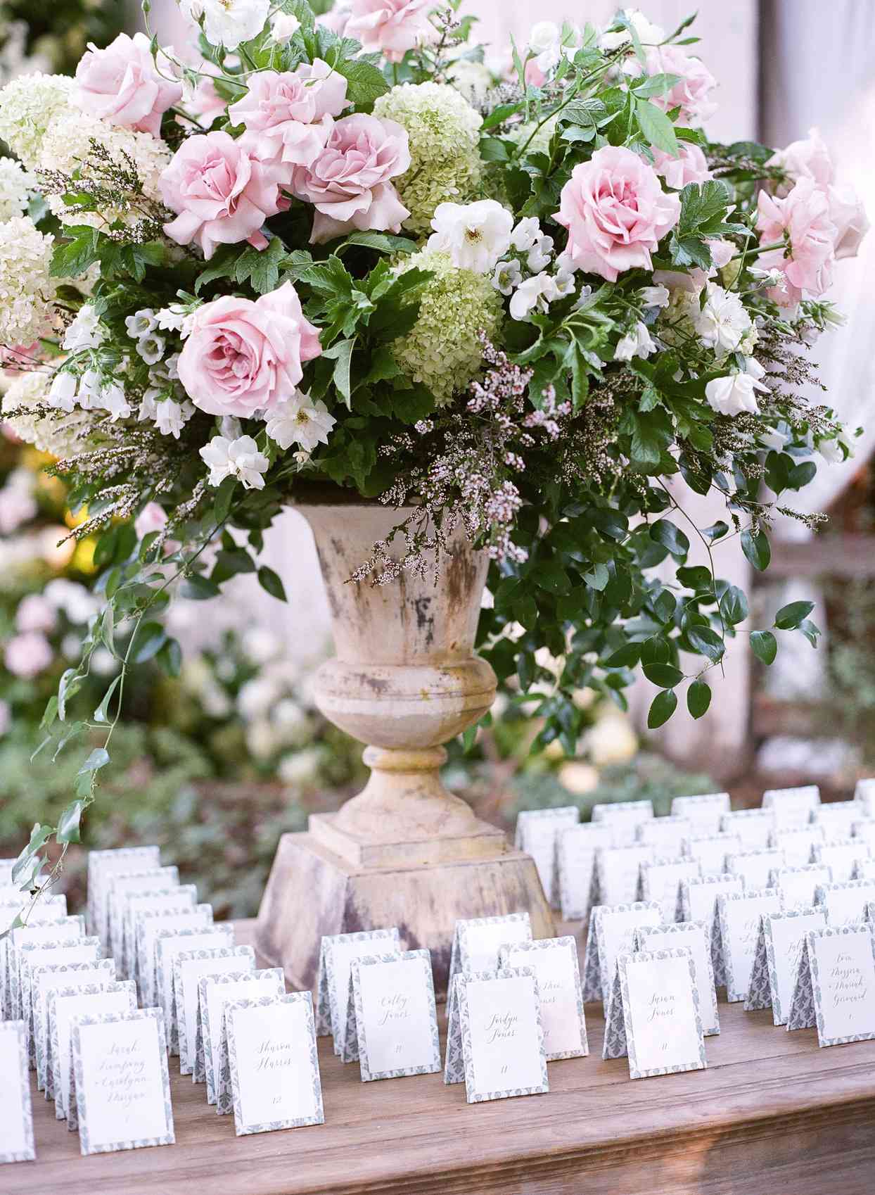 wooden table lined with white escort cards and pink floral arrangement