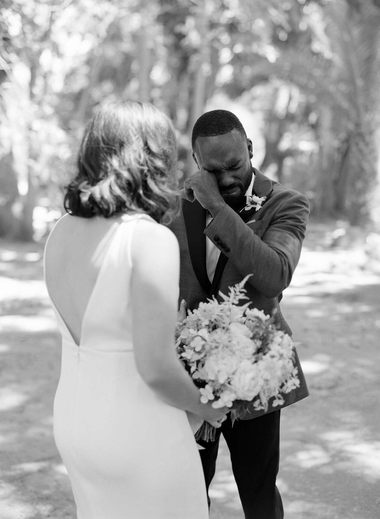 groom wipes away tear during first look with bride