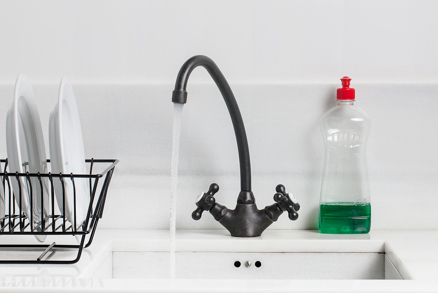 white kitchen sink with black faucet and dish rack
