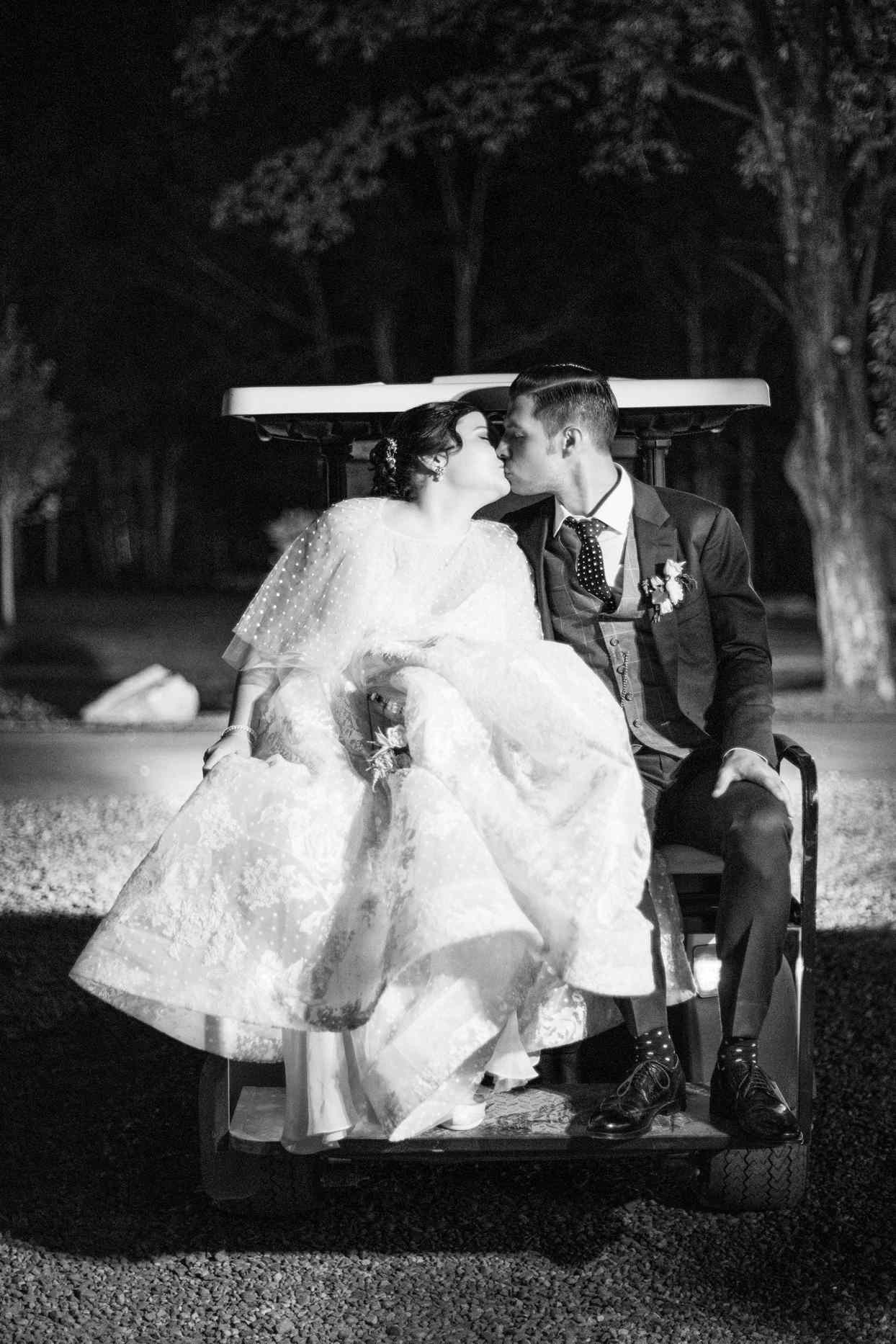 bride and groom kissing behind wedding golf cart