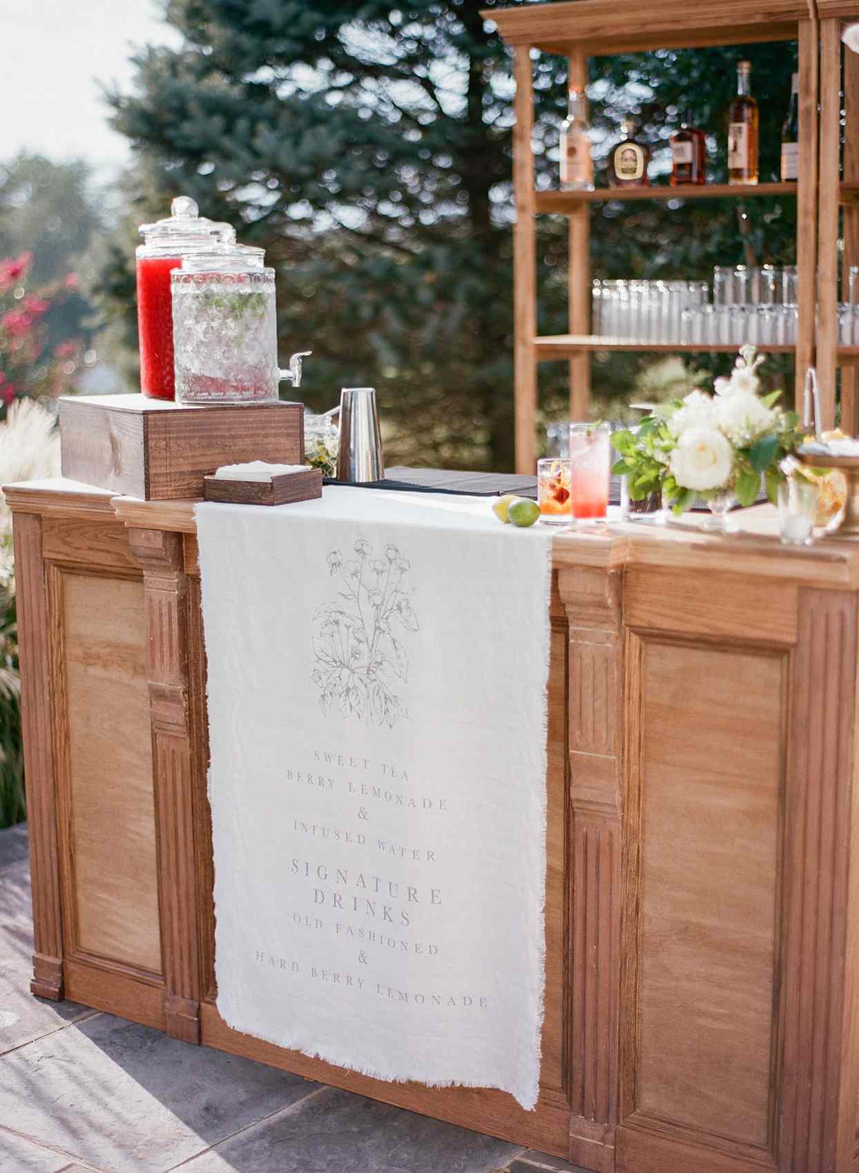 outdoor cocktail hour stand with white cloth cocktail sign