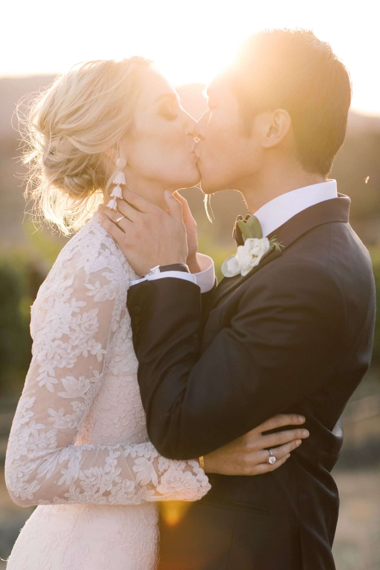 wedding couple kissing with sun shining in background