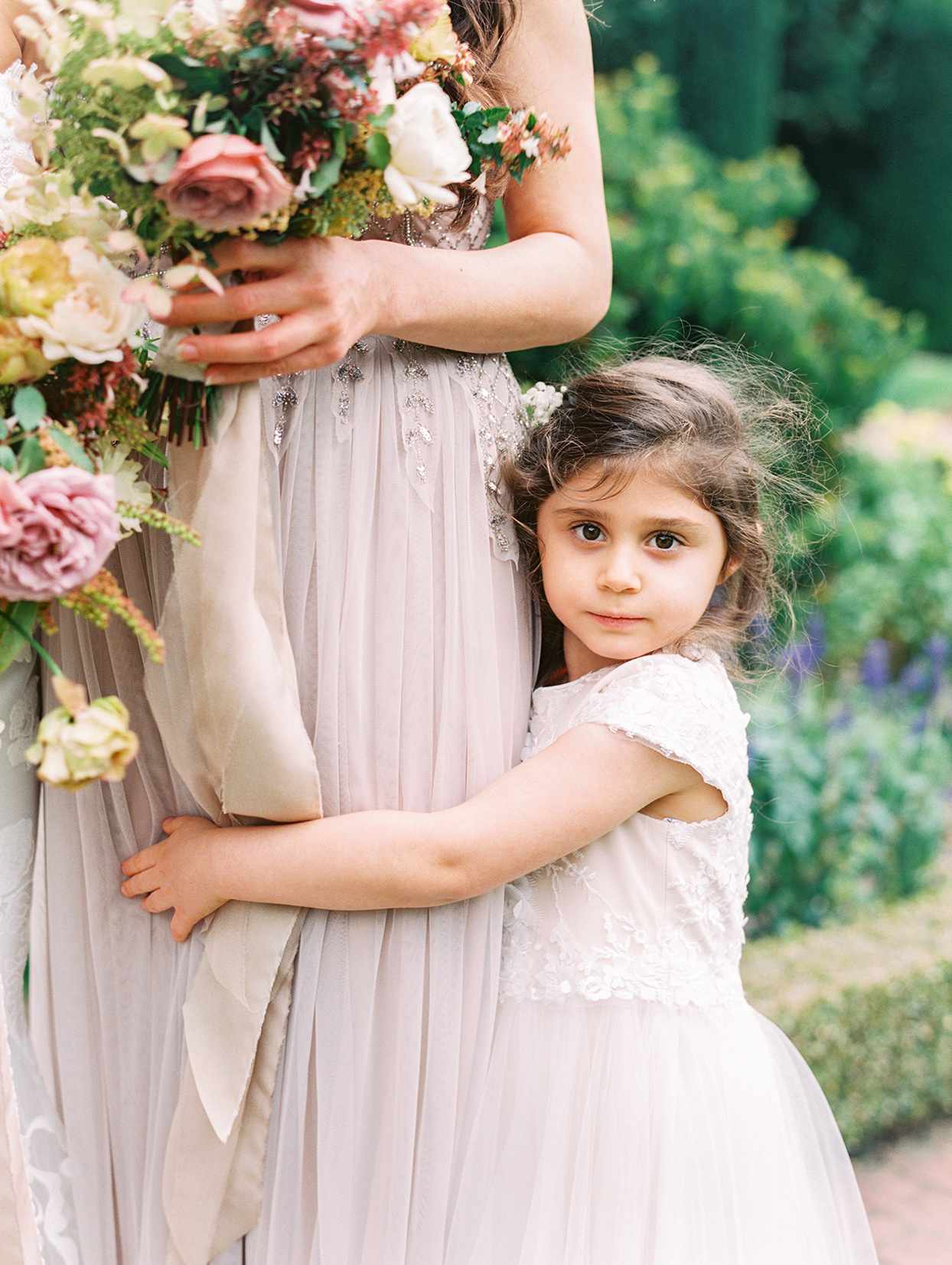 yalda anusha wedding flower girl hugging bridesmaid in pastel pink dress