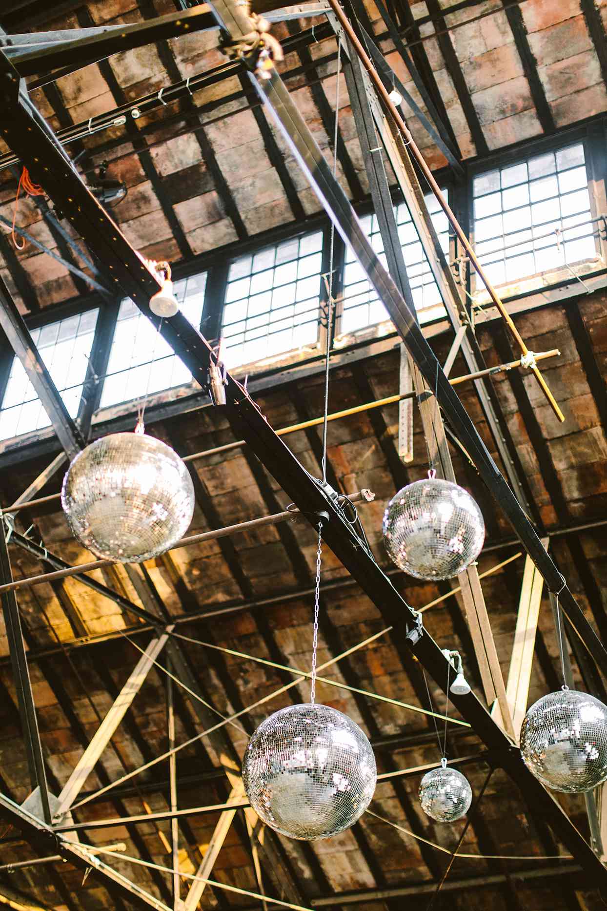 wedding disco balls hanging from industrial rafters