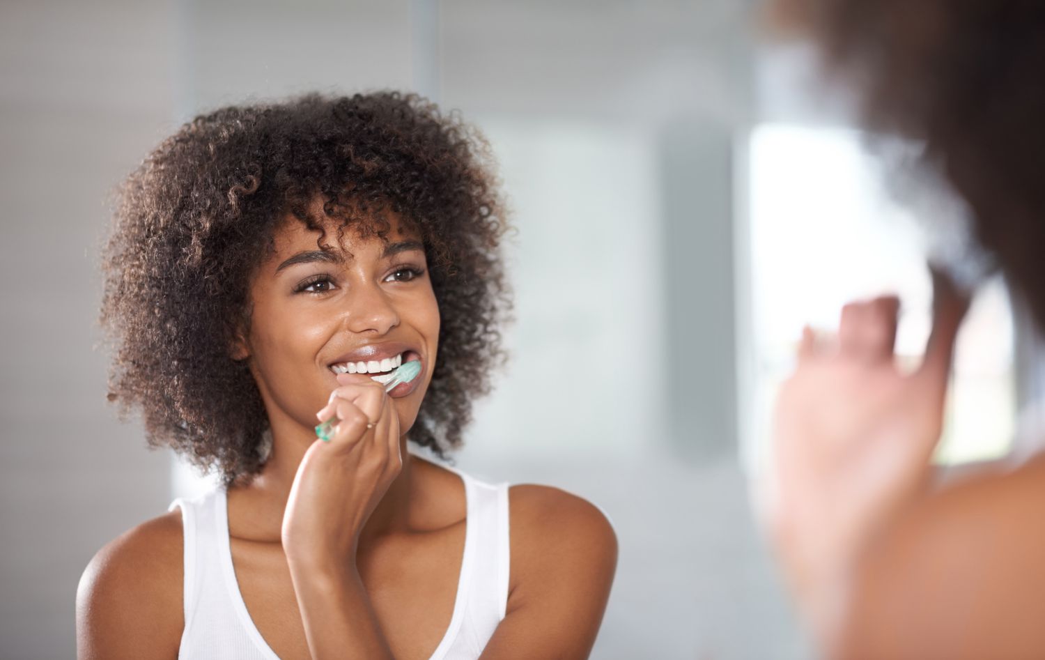 woman looking in mirror brushing teeth