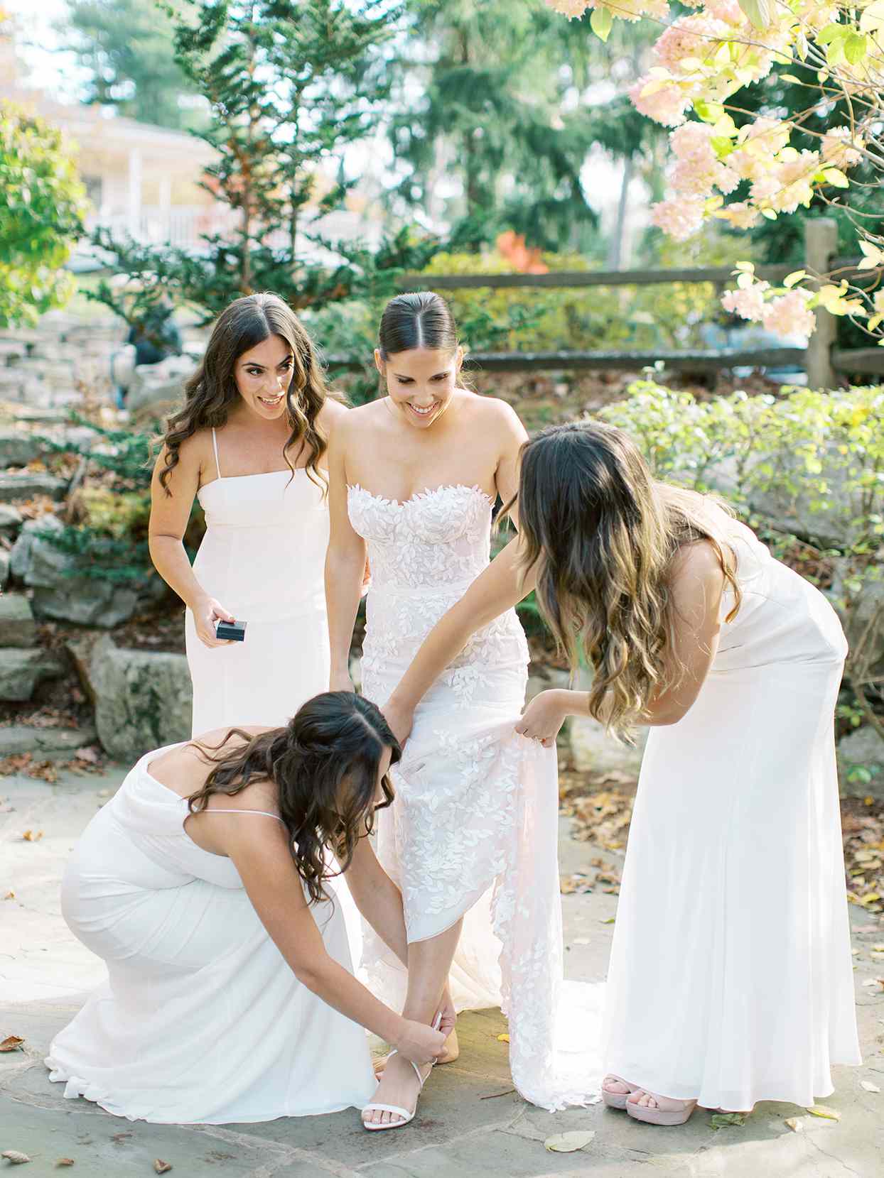 wedding bridesmaids helping bride strap on shoes