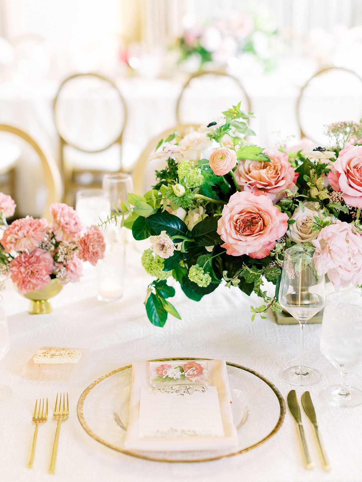 elegant reception place setting with golden accents and pink floral arrangement
