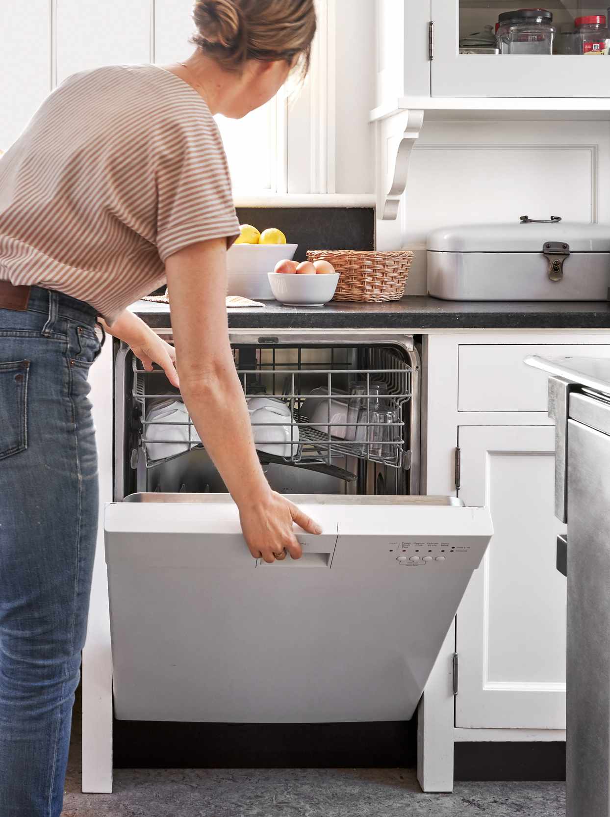 woman closing dishwasher in kitchen